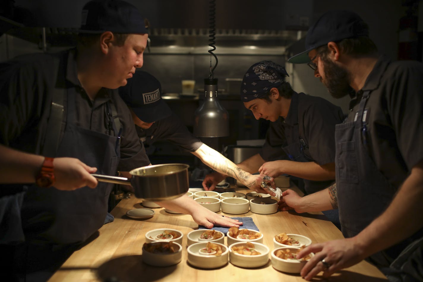 Chef and co-owner Cameron Cecchini, left plated the second course of onion ash gnocchi, Hen of the Woods, and pickled pearl onions with the help of Reed Evavold, co-owner Grisha Hammes, and Alex Dayton, from left.