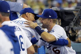 Los Angeles Dodgers manager Dave Roberts, left, greets Brian Dozier in the dugout during the ninth inning of the team's baseball game against the Milw