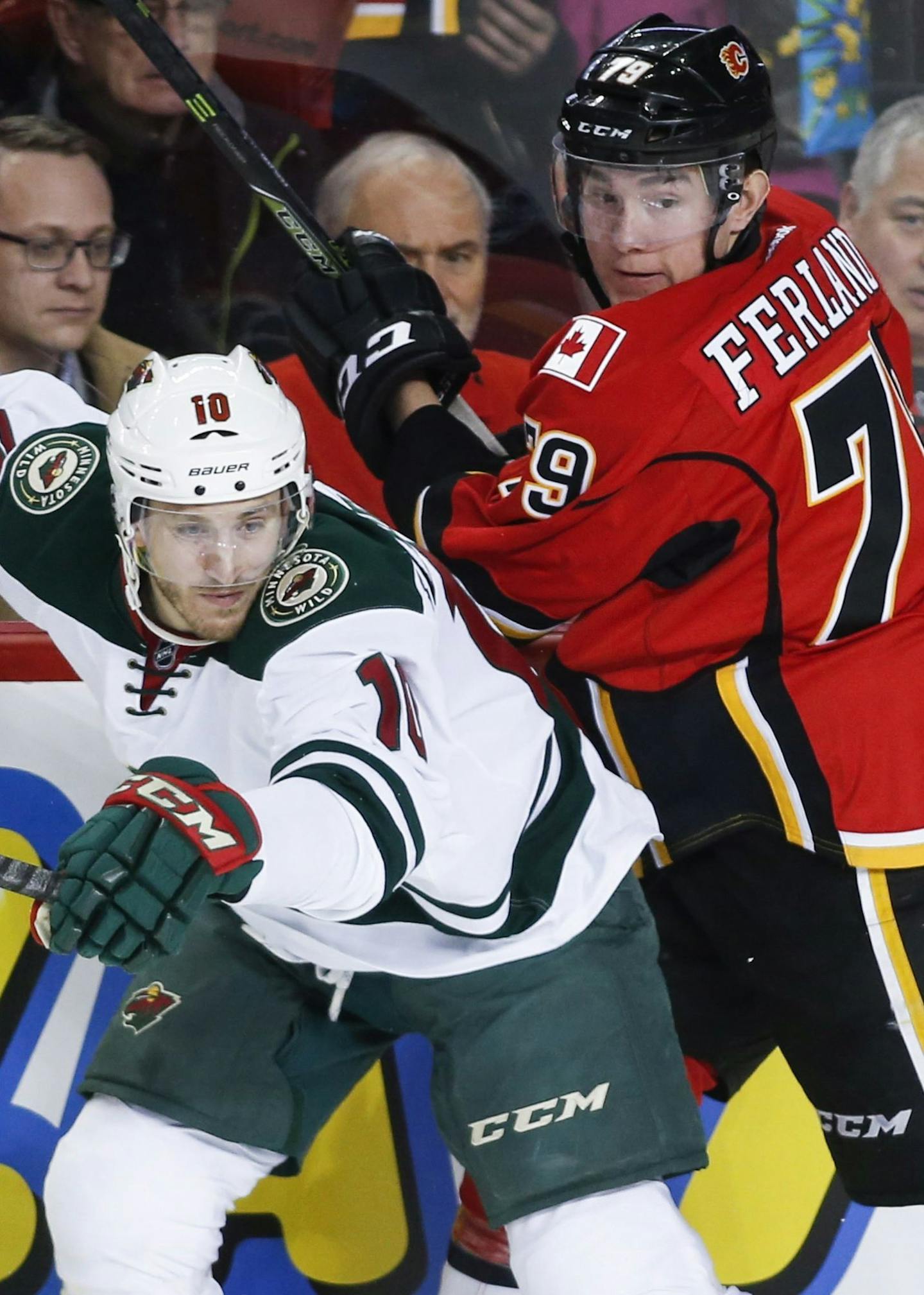 Minnesota Wild center Jordan Schroeder (10) checks Calgary Flames left wing Micheal Ferland (79) during the first period of an NHL hockey game Wednesday, Feb. 1, 2017, in Calgary, Alberta. (Jeff McIntosh/The Canadian Press via AP)