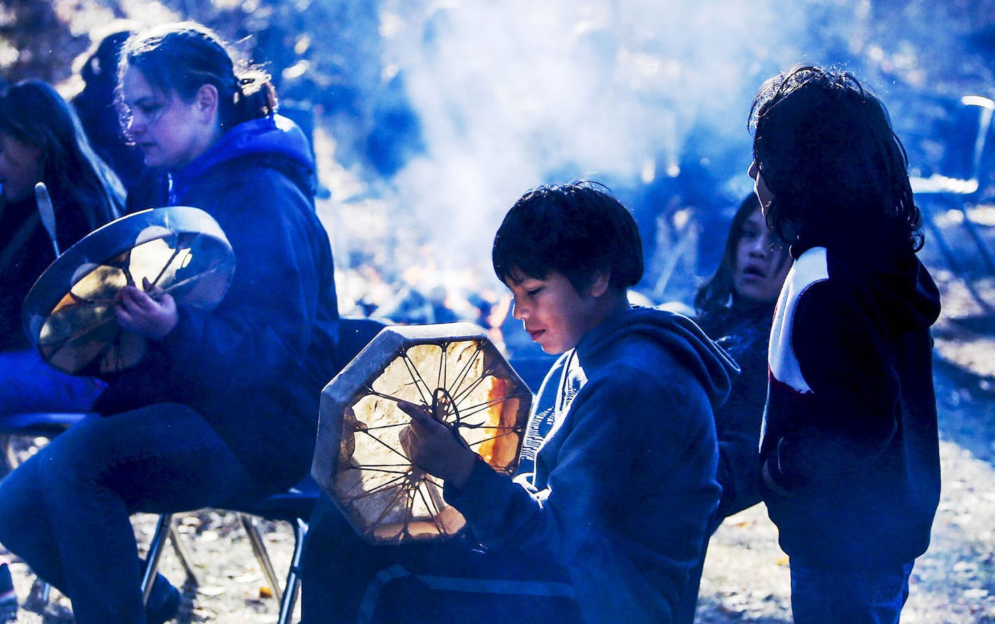 Niigaane School teacher Kim Anderson drums and sings in Ojibwe and Niigaan student Jaiden Lightfeather, center, drums along in the school's outdoor classroom Monday, Oct. 20, 2014. Niigaane students stand to inherit the old metal pole building that is now the Bug-O-Nay-Ge-Shig High School.](DAVID JOLES/STARTRIBUNE)djoles@startribune The Bug O Nay Ge Shig School is a culturally based alternative school that opened in 1975 with a mission of serving Ojibwe children and has matured into a fully accr