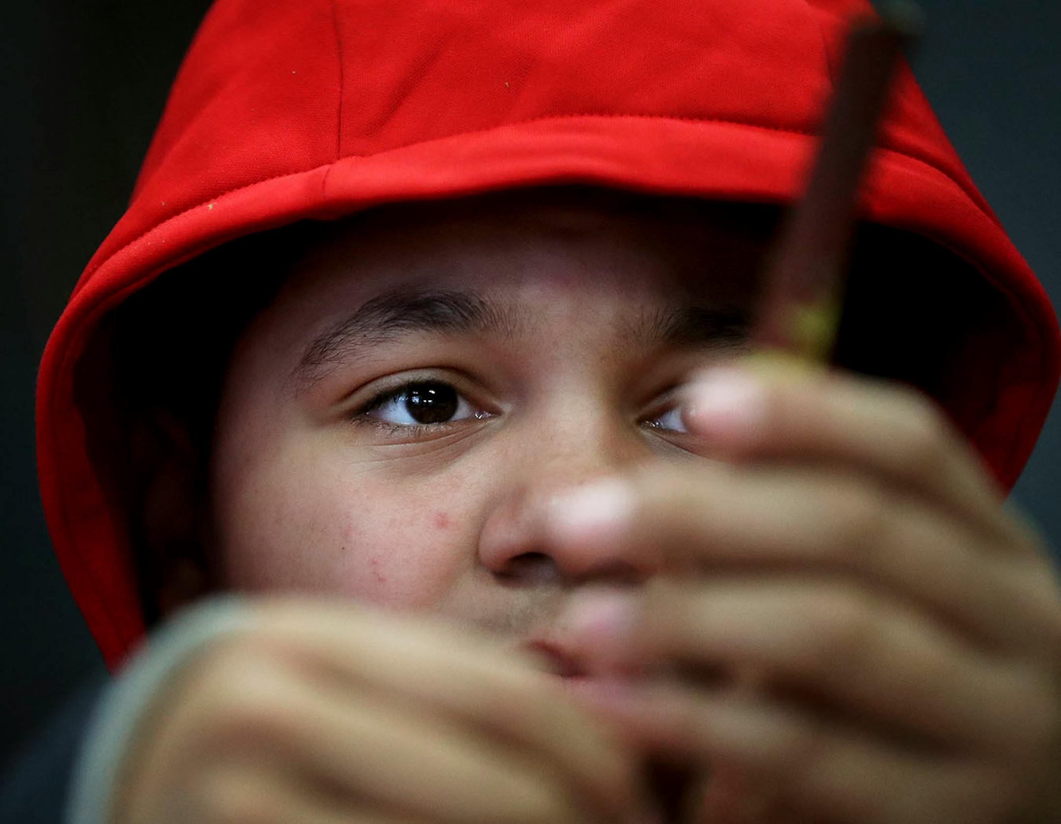 Lower Sioux Community member Elijah Walker, 14, looks over his red willow limb while using a spoon to shave off the bark from the red willow before harvesting the traditional tobacco from the limb.