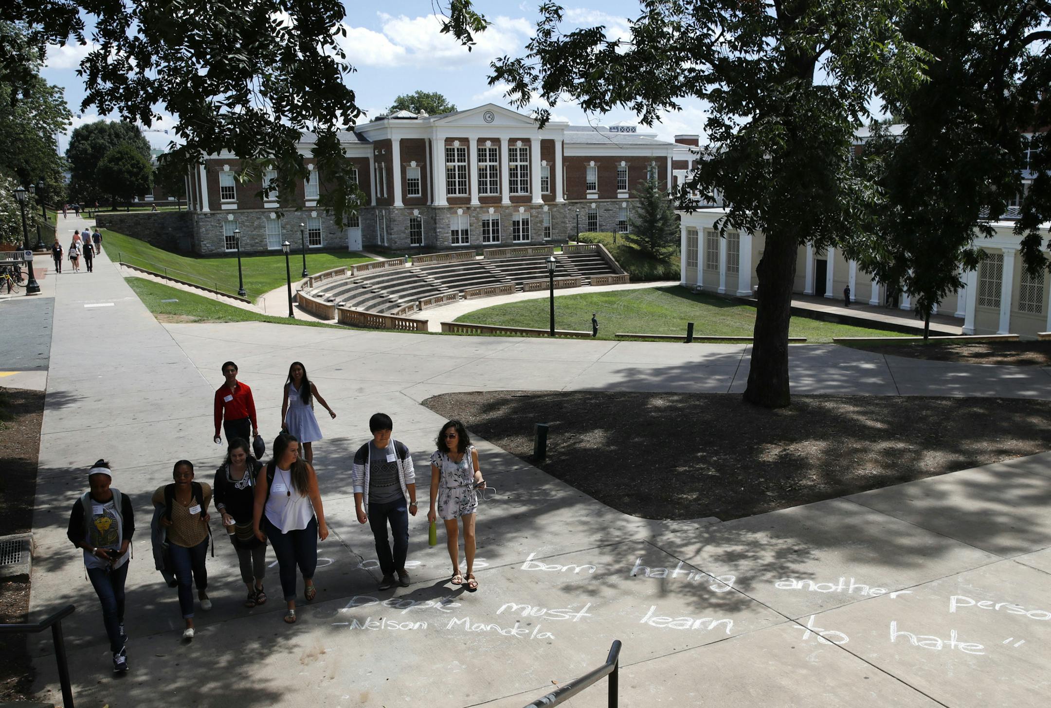 Students walks past a quote in chalk credited to Nelson Mandela at the University of Virginia, Friday, Aug. 18, 2017, in Charlottesville, Va., a week after a white nationalist rally took place on campus. The quote says "No one is born hating another person...people must learn to hate." (AP Photo/Jacquelyn Martin)