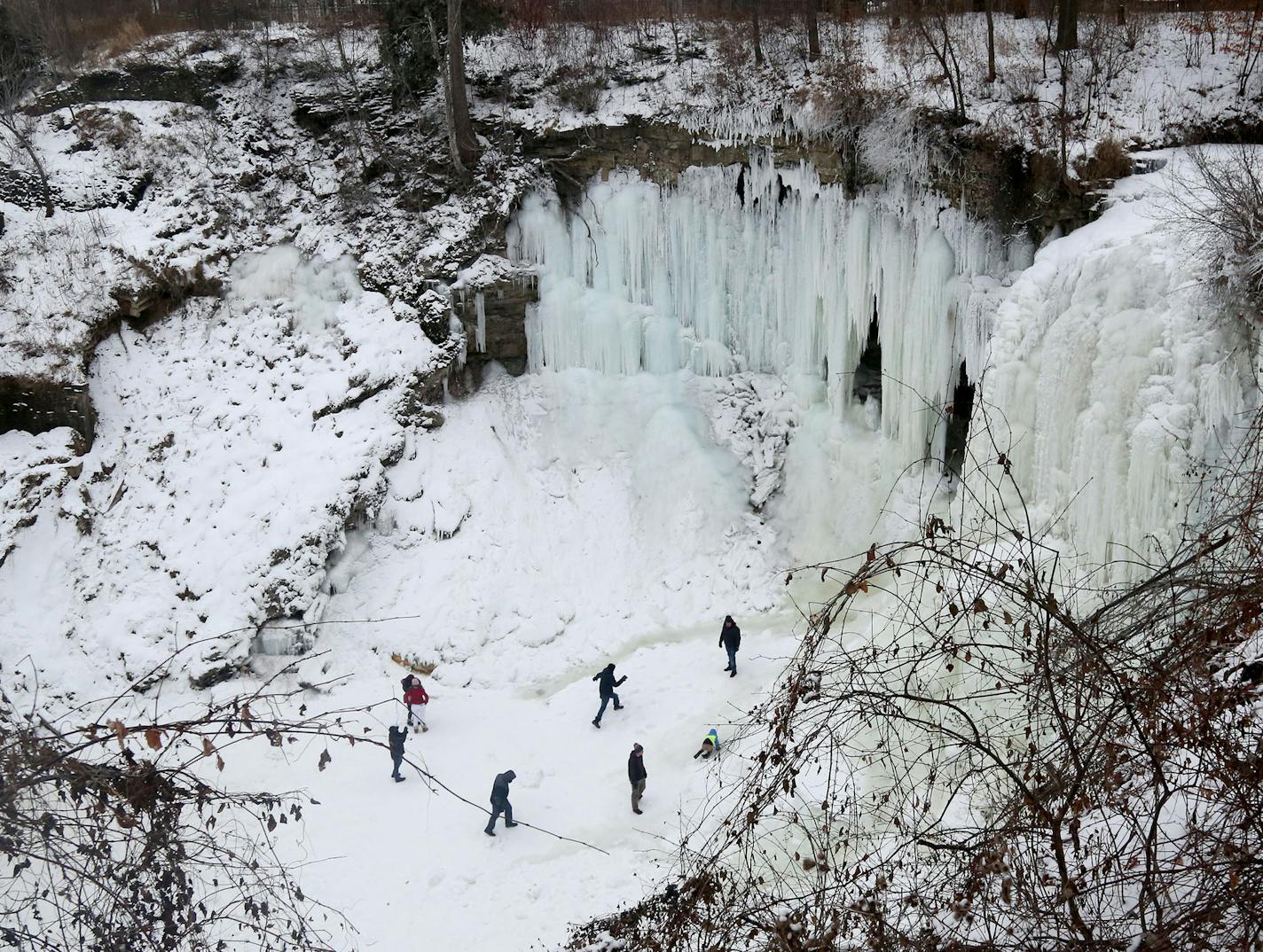 Thrill seekers, including some children with their parents, walk on the frozen waters beneath Minnehaha Falls Tuesday, Jan. 2, 2018, in Minneapolis, MN. Thrill seekers are skirting signs and police to get onto the frozen falls and creek for selfies and the chance to explore. While the waters are mostly frozen, the moving creek flows under their feet and if one were to break through the ice it could mean certain death.] DAVID JOLES &#xef; david.joles@startribune.com With the recent cold spell, Mi