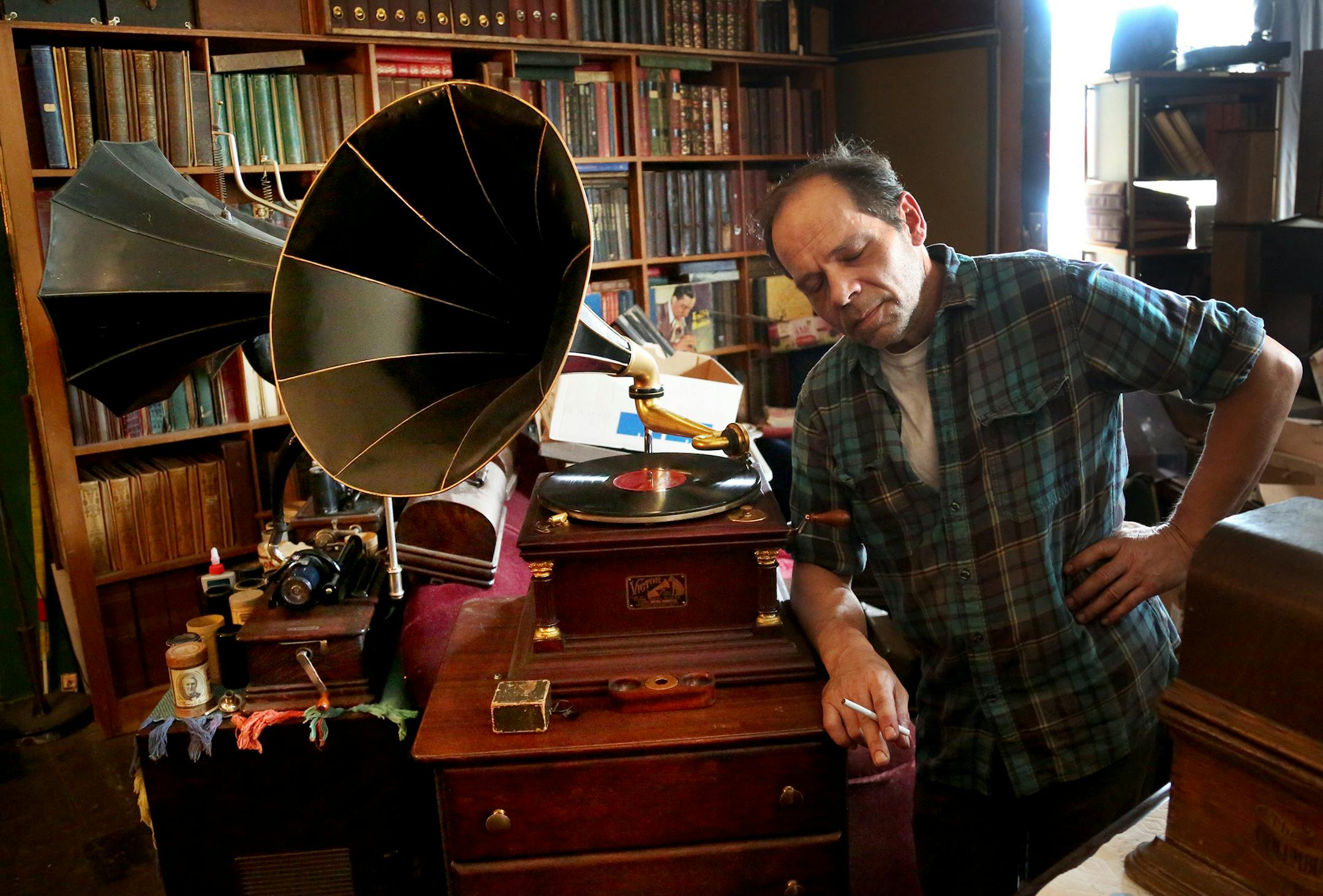 Vintage Music owner Scott Holthus closes his eyes while listening to a record in his store. He sells solely 78s along with restored consoles and phonographs.