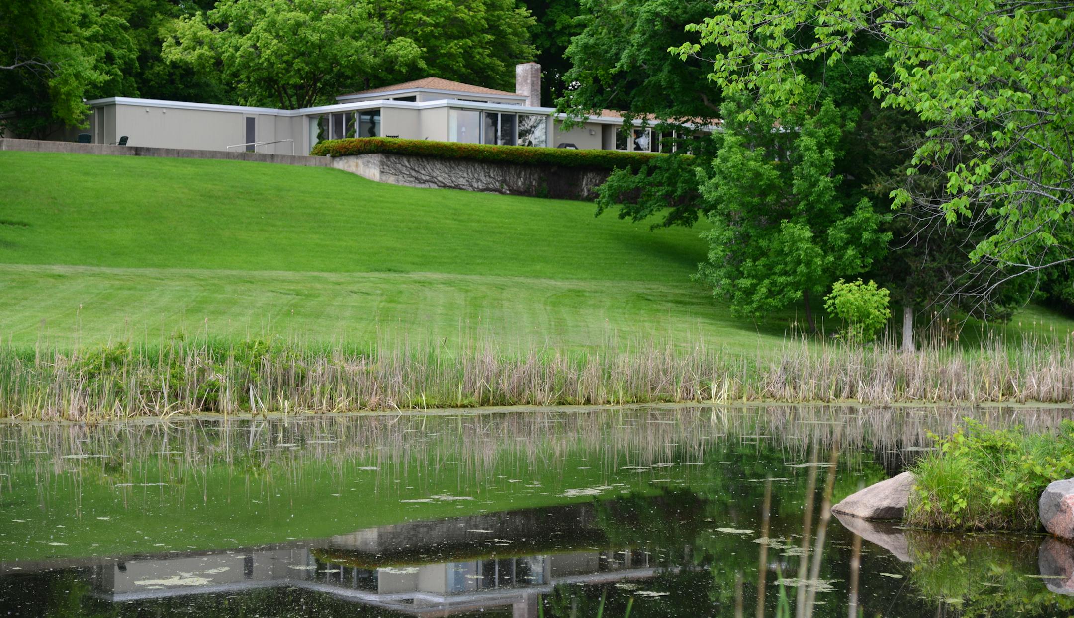 The house sits above a heart shaped reflecting pond] When Doug Dayton bought nearly 100 acres of woods and fields just a few minutes north of Wayzata, he vowed to create a refuge of waving grasslands, knotted walking trails and placid ponds. The place would become a refuge from the demands of running the family department store, and a place to raise his family. He restored nearly 40 acres of native prairie grasslands and forbs, and hand-planted hundreds of plum trees, oaks and pines that now tow