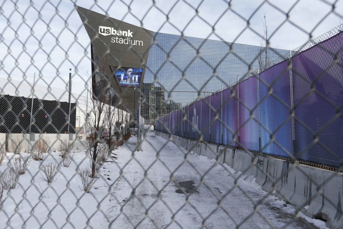 In this Jan. 18, 2018 photo, U.S. Bank Stadium, home of the upcoming Super Bowl, is seen through the protective concrete and chain link fence, part of which was already covered with wrap, in Minneapolis where security is tight for the big NFL game. The downtown location of the Feb. 4 Super Bowl has presented some challenges for authorities, who have had to get creative as they carved a secure perimeter around businesses and a major hospital near U.S. Bank Stadium.