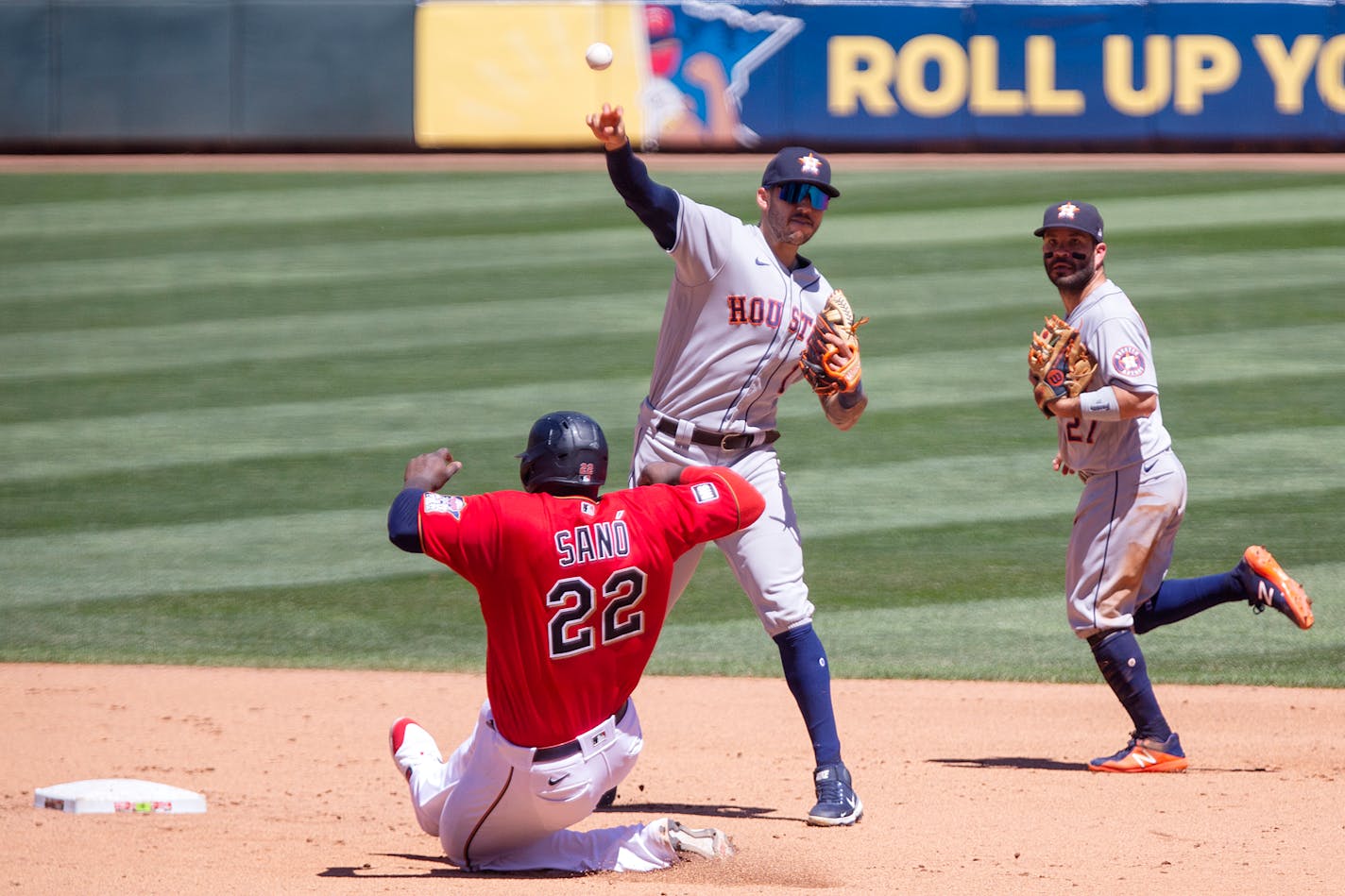 Houston Astros shortstop Carlos Correa (1) throws to first on a double play with Minnesota Twins first baseman Miguel Sano (22) out at second and Astros' Jose Altuve (27) backing up in the fourth inning of a baseball game, Sunday, June 13, 2021, in Minneapolis. (AP Photo/Andy Clayton-King)