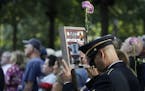 A man holds a photo of a victim during a ceremony marking the 18th anniversary of the attacks of Sept. 11, 2001 at the National September 11 Memorial,