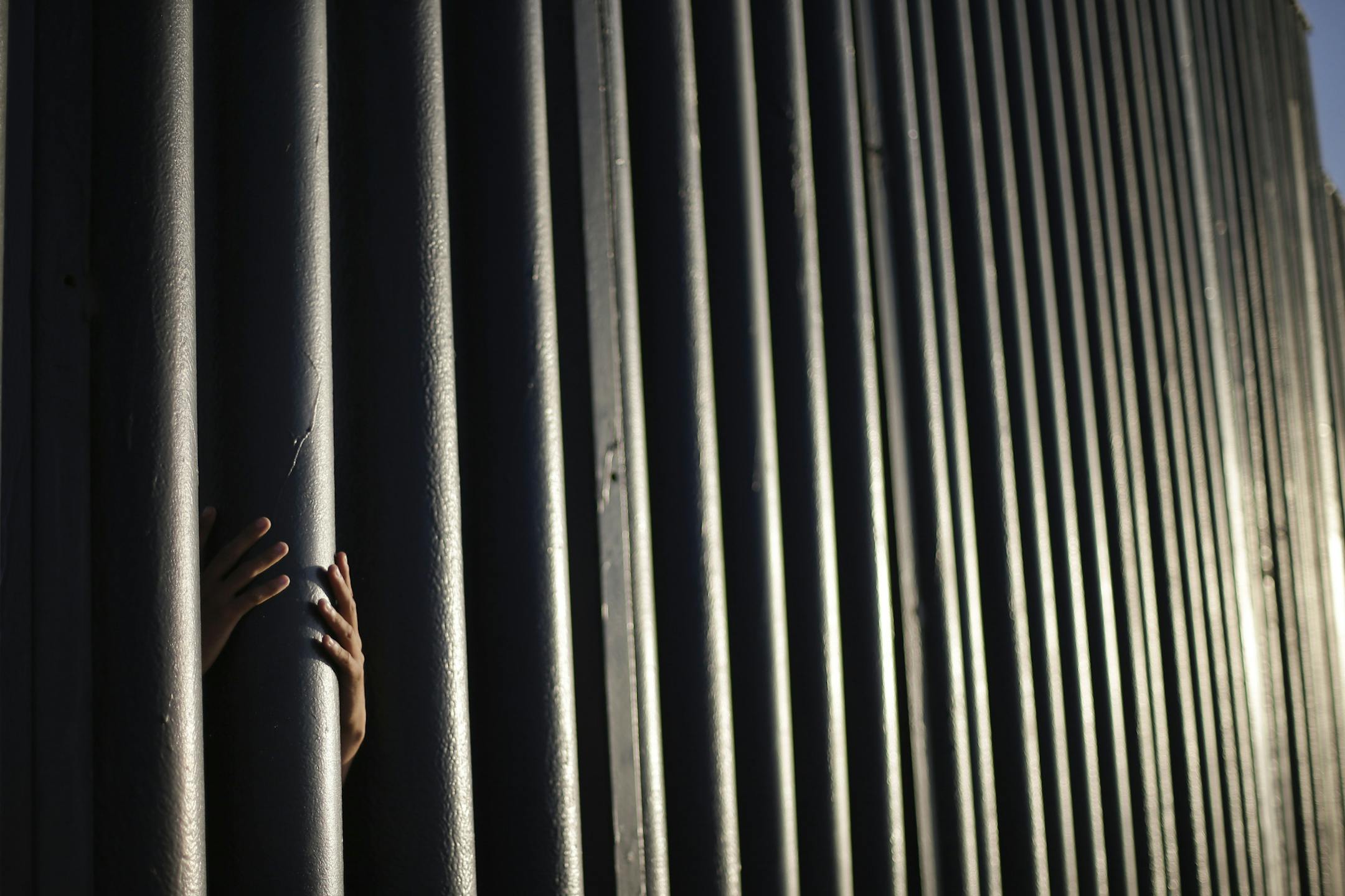 In this June 13, 2013 file photo, Daniel Zambrano, of Tijuana, Mexico, holds one of the bars that make up the border wall separating the U.S. and Mexico where the border meets the Pacific Ocean in San Diego.