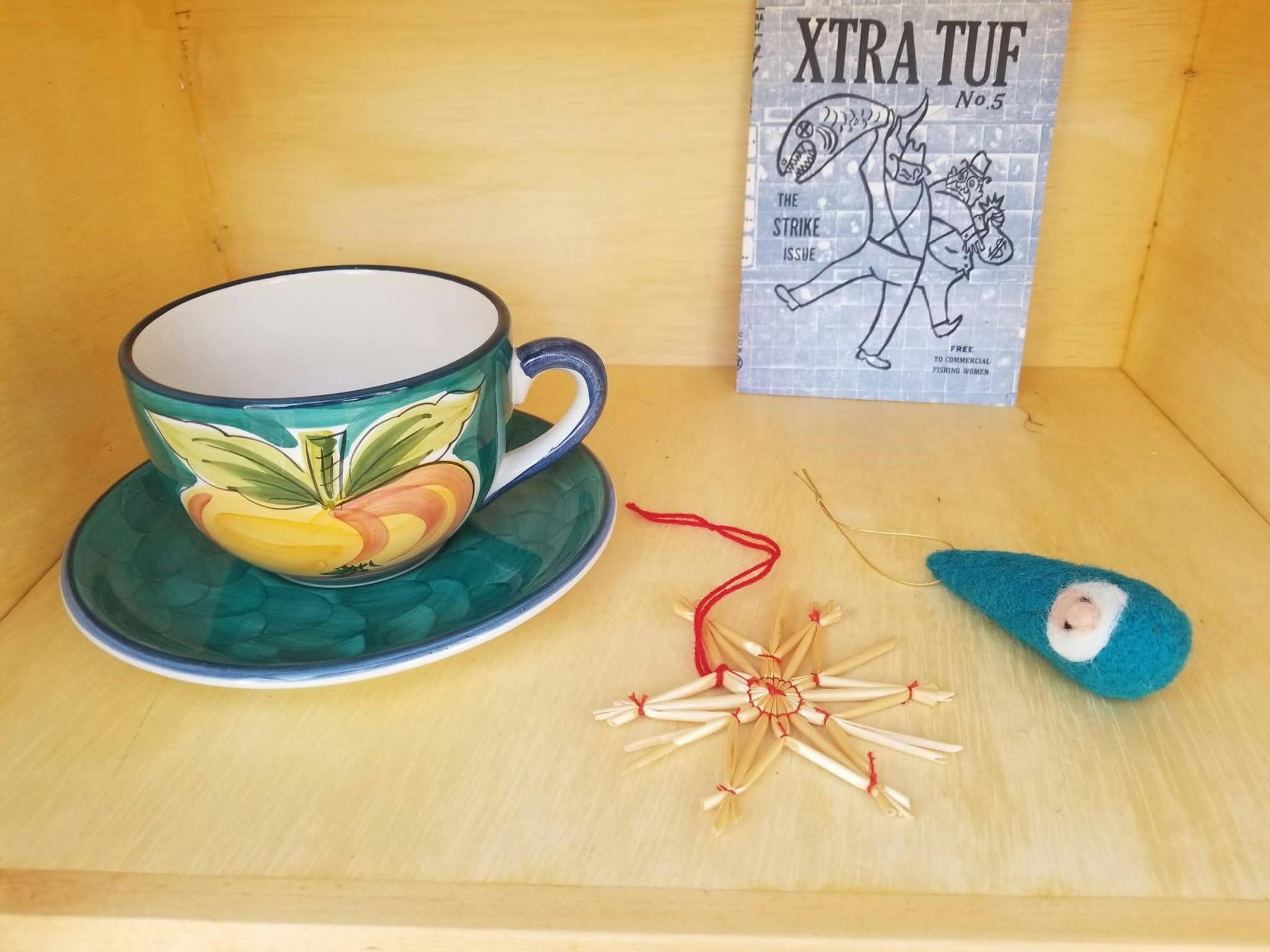 A handpainted mug and saucer and homemade ornaments sit in a wooden box.