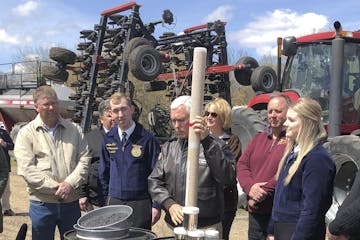 Vice President Mike Pence, center, holds a tube of soy beans as he tours the R & J Johnson Farms in Glyndon, Minn., Thursday, May 9, 2019, to talk abo