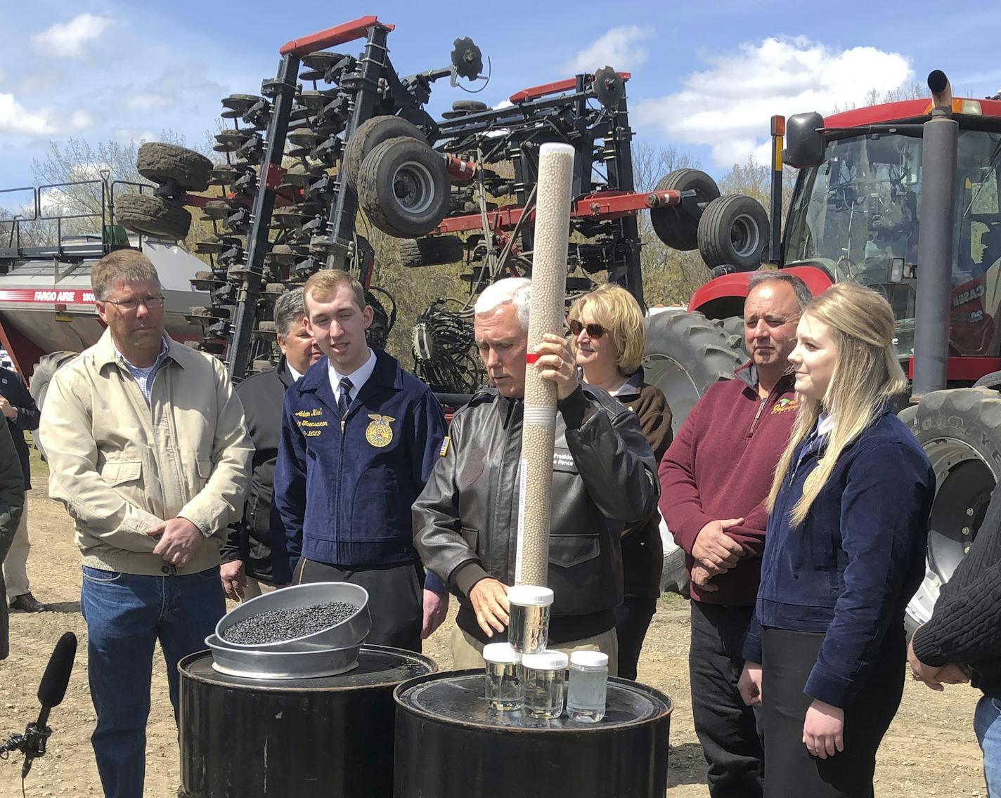 Vice President Mike Pence, center, holds a tube of soy beans as he tours the R & J Johnson Farms in Glyndon, Minn., Thursday, May 9, 2019, to talk about the Trump administration's trade agreement with Canada and Mexico. Famers who visited with Pence emphasized the importance of selling soy beans as Minnesota ranks third among all states in soy bean production. (AP Photo/Dave Kolpack) ORG XMIT: RPDK101