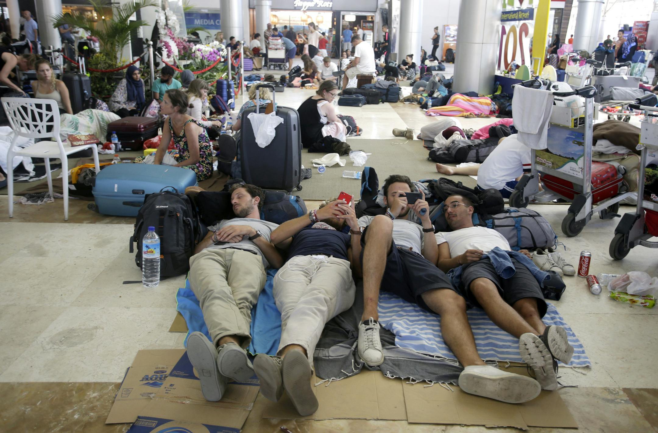 Foreign tourists rest on the floor while waiting for their flights at Lombok International Airport, following an earthquake in Praya, Lombok Island, Indonesia, Tuesday, Aug. 7, 2018. Thousands left homeless by the powerful quake that ruptured roads and flattened buildings on the Indonesian tourist island of Lombok sheltered Monday night in makeshift tents as authorities said rescuers hadn't yet reached all devastated areas. (AP Photo/Firdia Lisnawati)