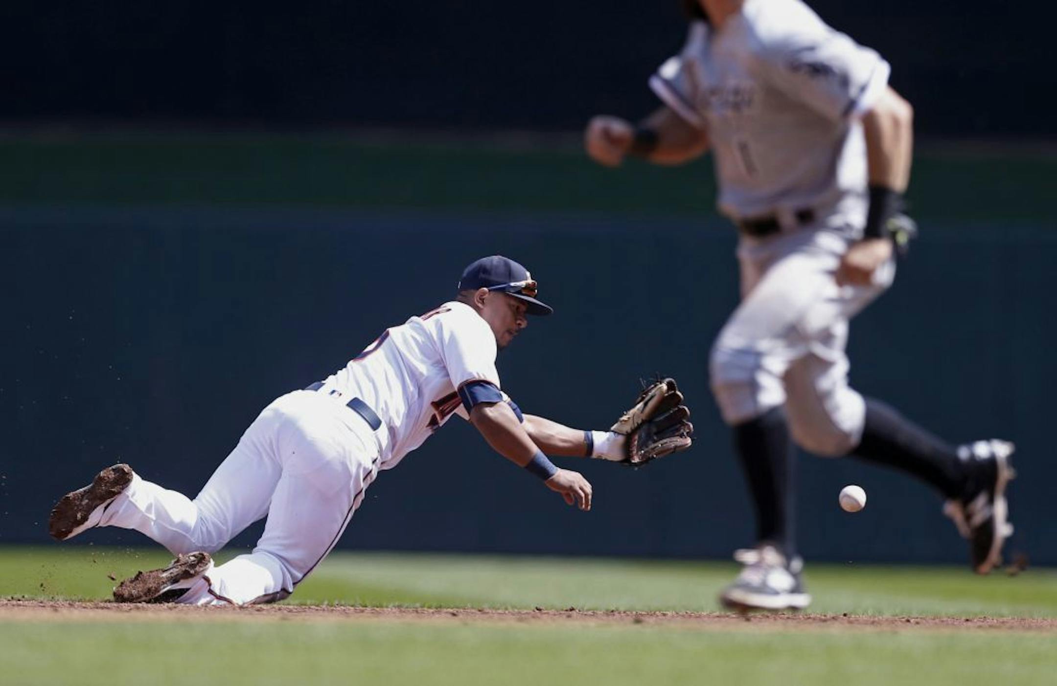 Chicago White Sox's Adam Eaton, right, races to third as Minnesota Twins shortstop Eduardo Escobar dives for a grounder after Chicago's Todd Frazier hit into a fielder's choice in the third inning of a baseball game Thursday, April 14, 2016, in Minneapolis. Escobar relayed the ball to second to force out Jose Abreu.