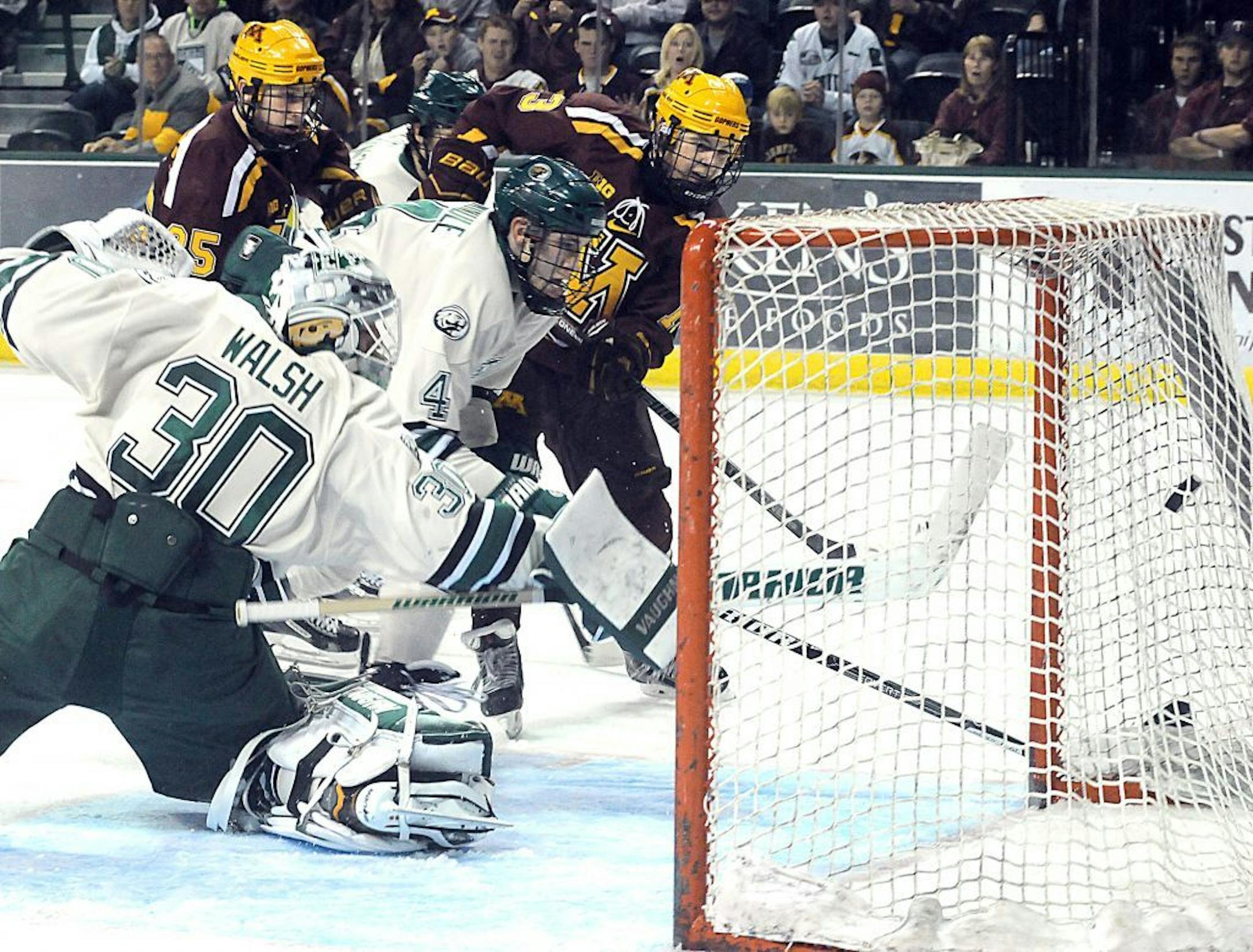 Minnesota's Taylor Cammarata (13) scores a goal against Bemidji State goalie Andrew Walsh during an NCAA college hockey game Saturday, Oct. 19, 2013, in Bemidji, Minn.