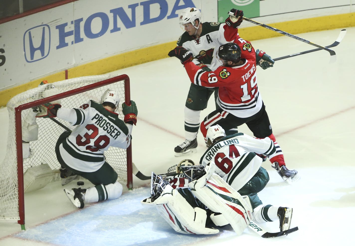 Minnesota Wild defenseman Nate Prosser (39) chases the puck into the goal as Chicago Blackhawks center Jonathan Toews (19) scores during the third period of their game Sunday night at United Center in Chicago.