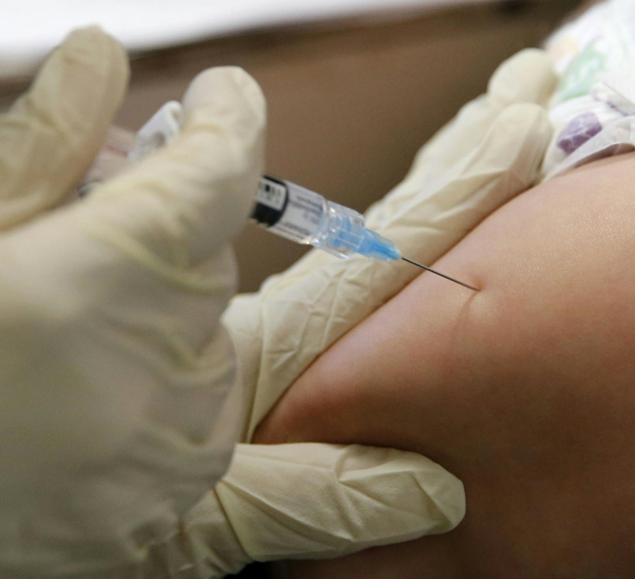 FILE - In this March 8, 2019 file photo, Rambo Islas, 8 months, is held by his mother Maria Islas, as he gets a vaccine shot administered by RN Nicole Ives at the Dallas County Health & Human Services immunization clinic in Dallas. A Texas Department of Health Services report shows the number of people in the state who chose to not immunize their children for non-medical reasons has jumped in the in 2018-2019 school year despite a record-breaking measles outbreak in the U.S. (Vernon Bryant/The D