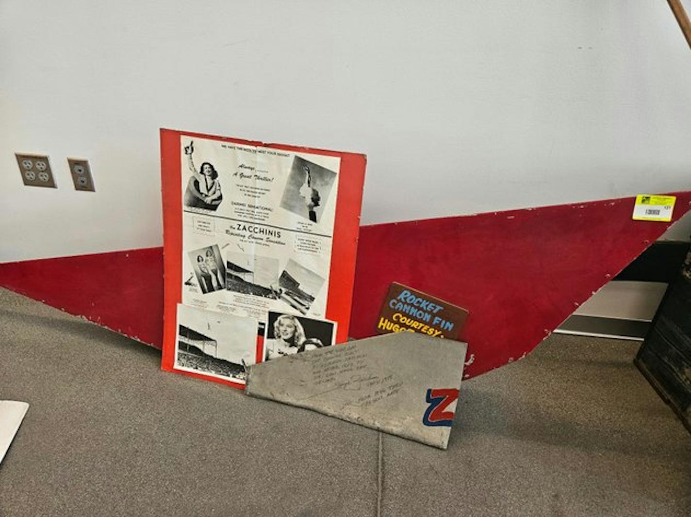 A photo of a red panel and a board with advertising slogans about a human cannonball act.