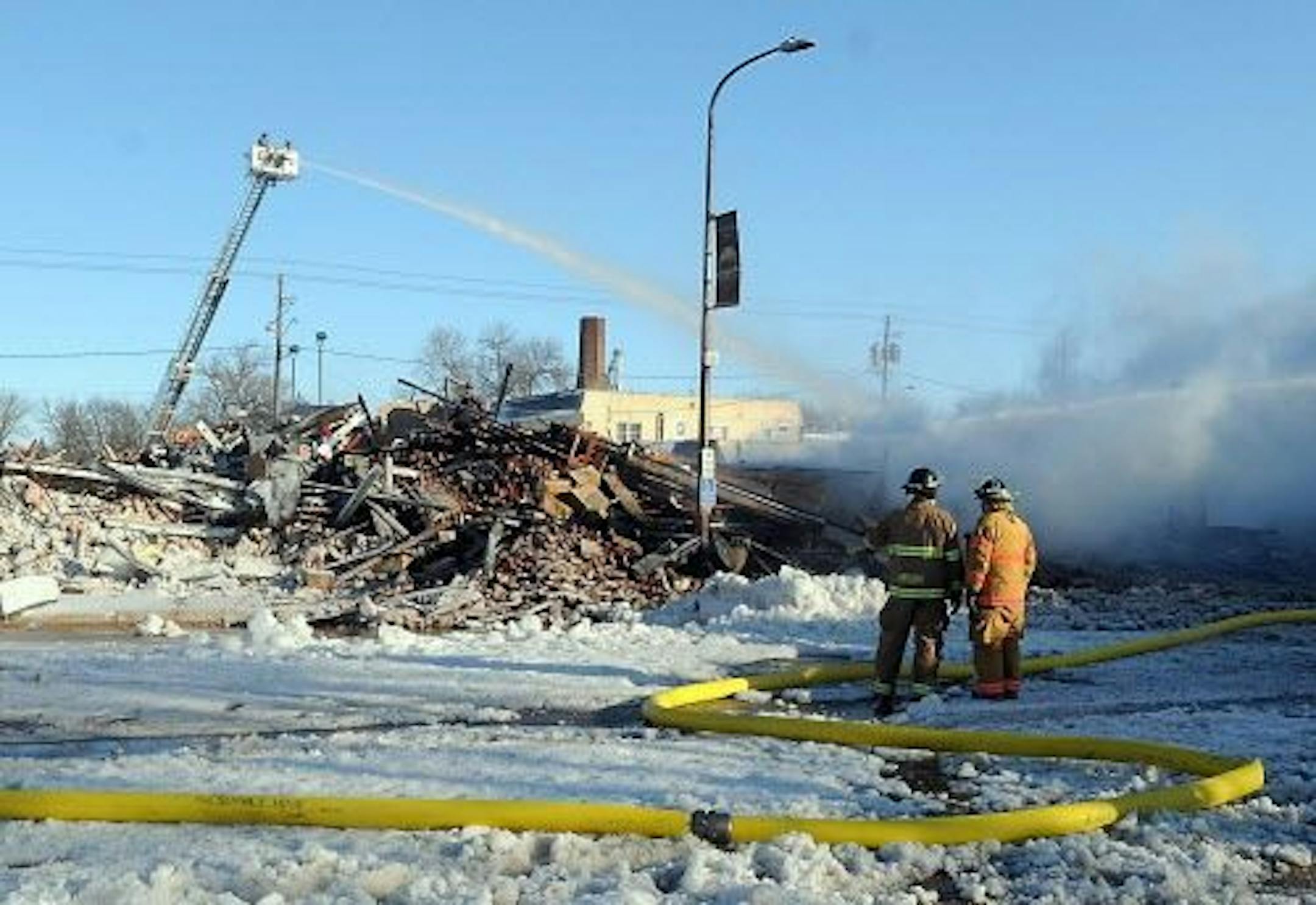 Firefighters spray water on the remains of one of the buildings destroyed by an early morning fire in downtown Madelia, Minn. Wednesday, Feb. 3, 2016. The fire took out about two-thirds of the businesses on one side of Main Street, city administrator Jane Piepgras said.