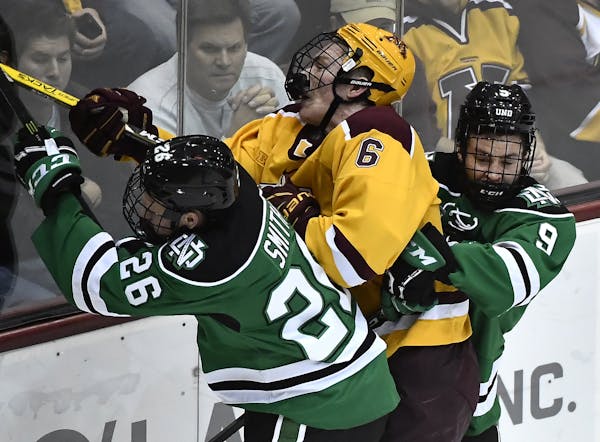 Minnesota Golden Gophers right defender Ryan Collins (6) took a hard check from North Dakota Fighting Hawks forward Cole Smith (26) and defenseman Dix