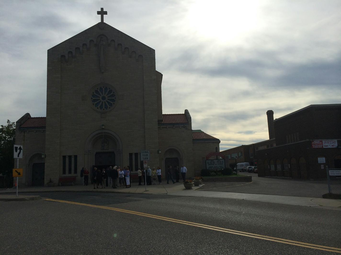 People huddle outside of Sacred Heart Church following a special mass in honor of fallen Officers Ron Ryan Jr. and Tim Jones. Ryan was shot in the church's parking lot decades ago.