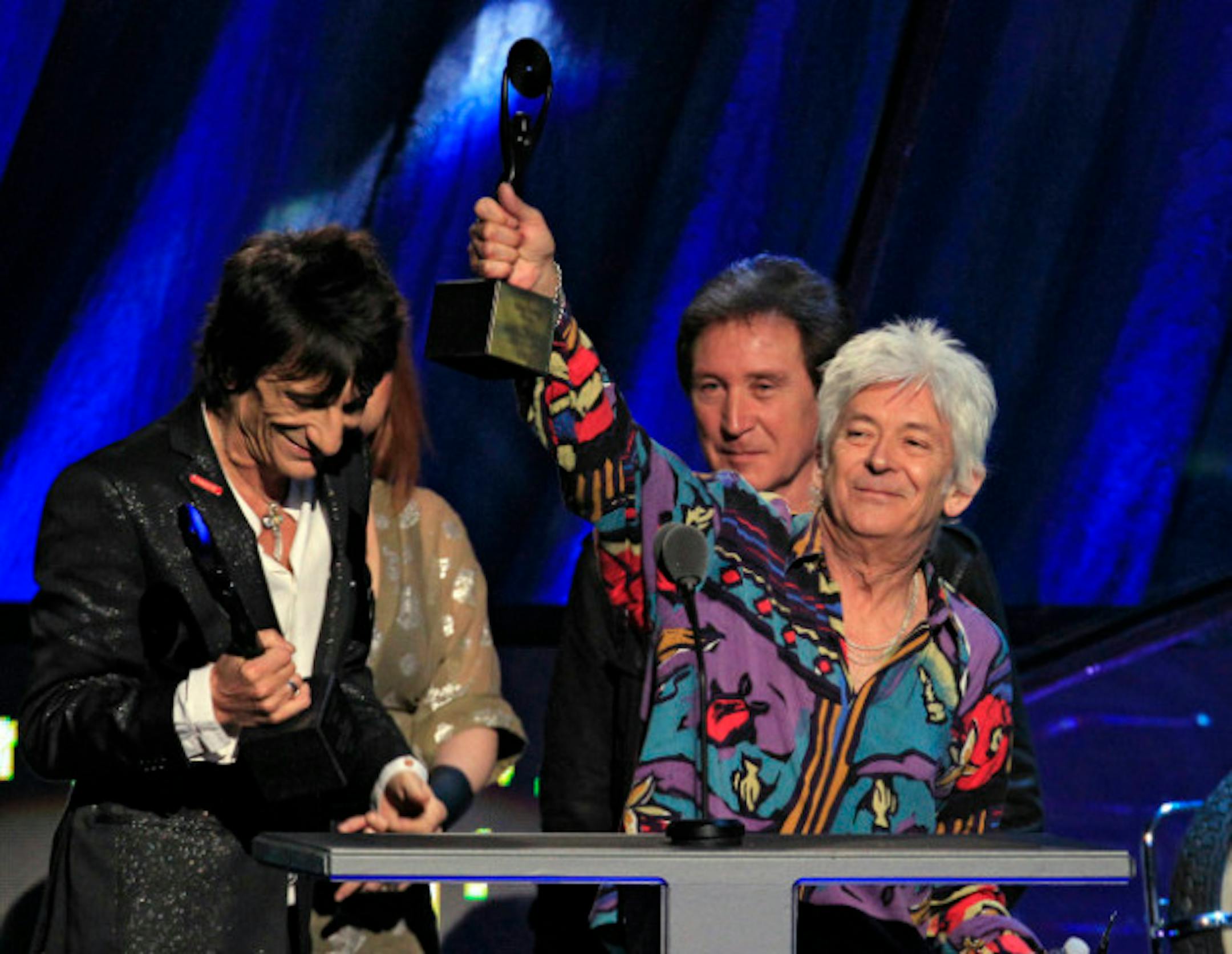 Ian McLagan raised his trophy at the Faces' induction into the Rock and Roll Hall of Fame in 2012, flanked by Ronnie Wood, left, and Kenney Jones. / Tony Dejak, Associated Press