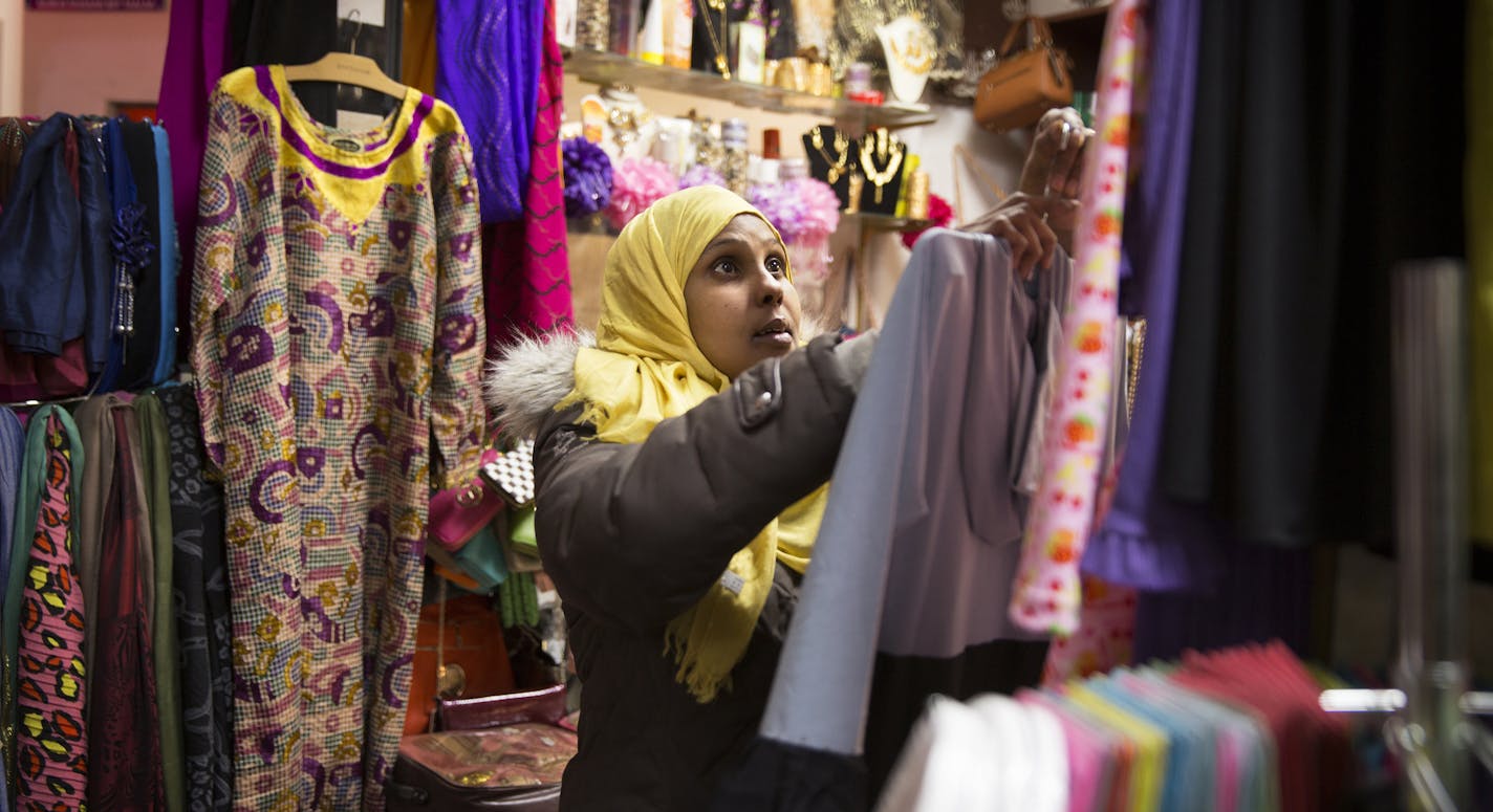 Amina Maie hangs up clothing for sale inside her shop at Karmel Mall in Minneapolis on Friday, February 20, 2015. ] LEILA NAVIDI leila.navidi@startribune.com / BACKGROUND INFORMATION: The project to add an additional floor to Minneapolis' oldest Somali mall made news last year when part of the construction collapsed, cutting off electricity to neighboring businesses. Now, Basim Sabri, the Karmel Mall's owner, is showing off the newly completed makeover and mosque.