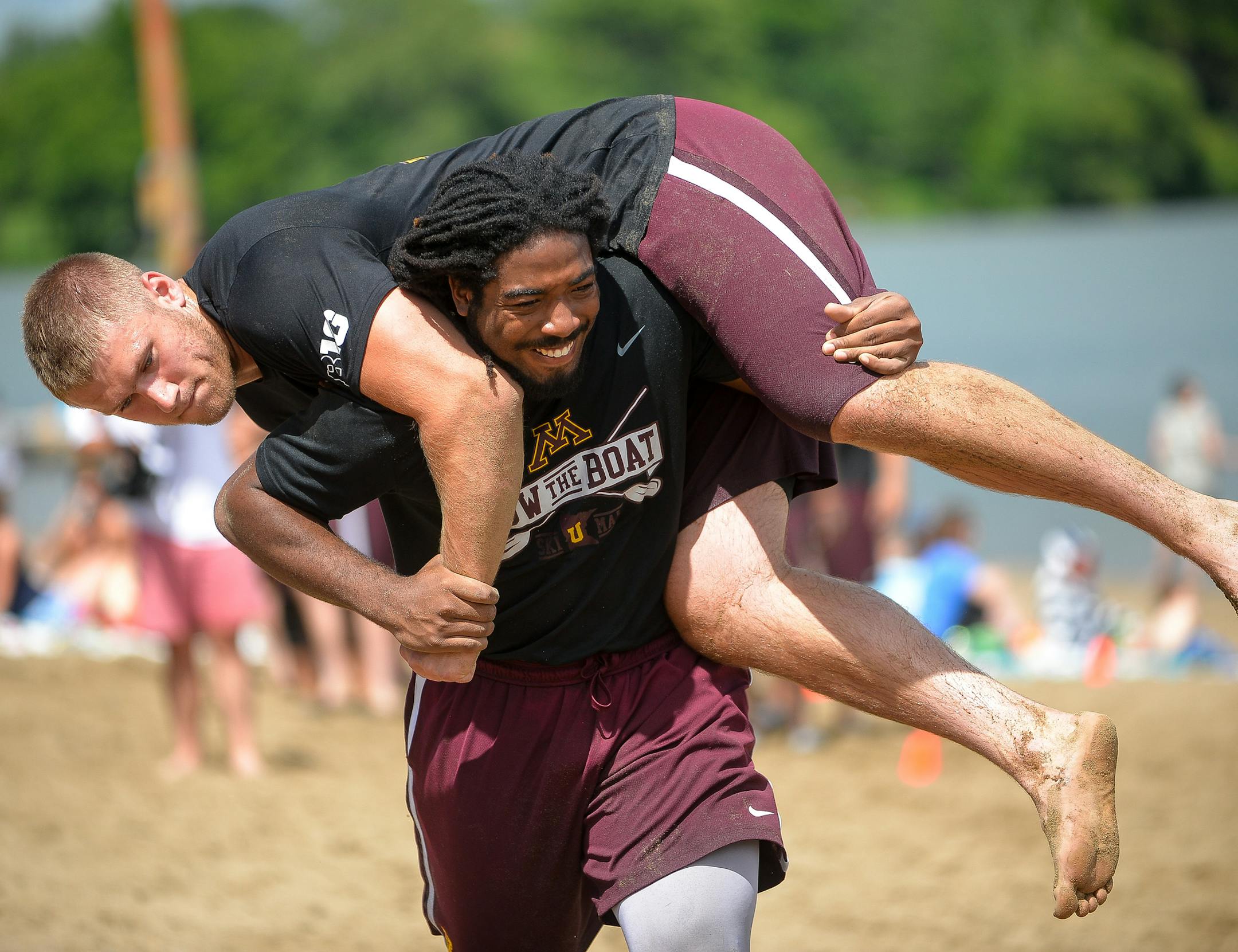 Gophers linebacker Everett Williams ran through the sand with tight end Bryce Witham hoisted over his shoulders during practice Friday at Lake Nokomis. ] AARON LAVINSKY ï aaron.lavinsky@startribune.com The University of Minnesota football team practiced on a beach on Lake Nokomis on Friday, June 23, 2017 in Minneapolis, Minn.
