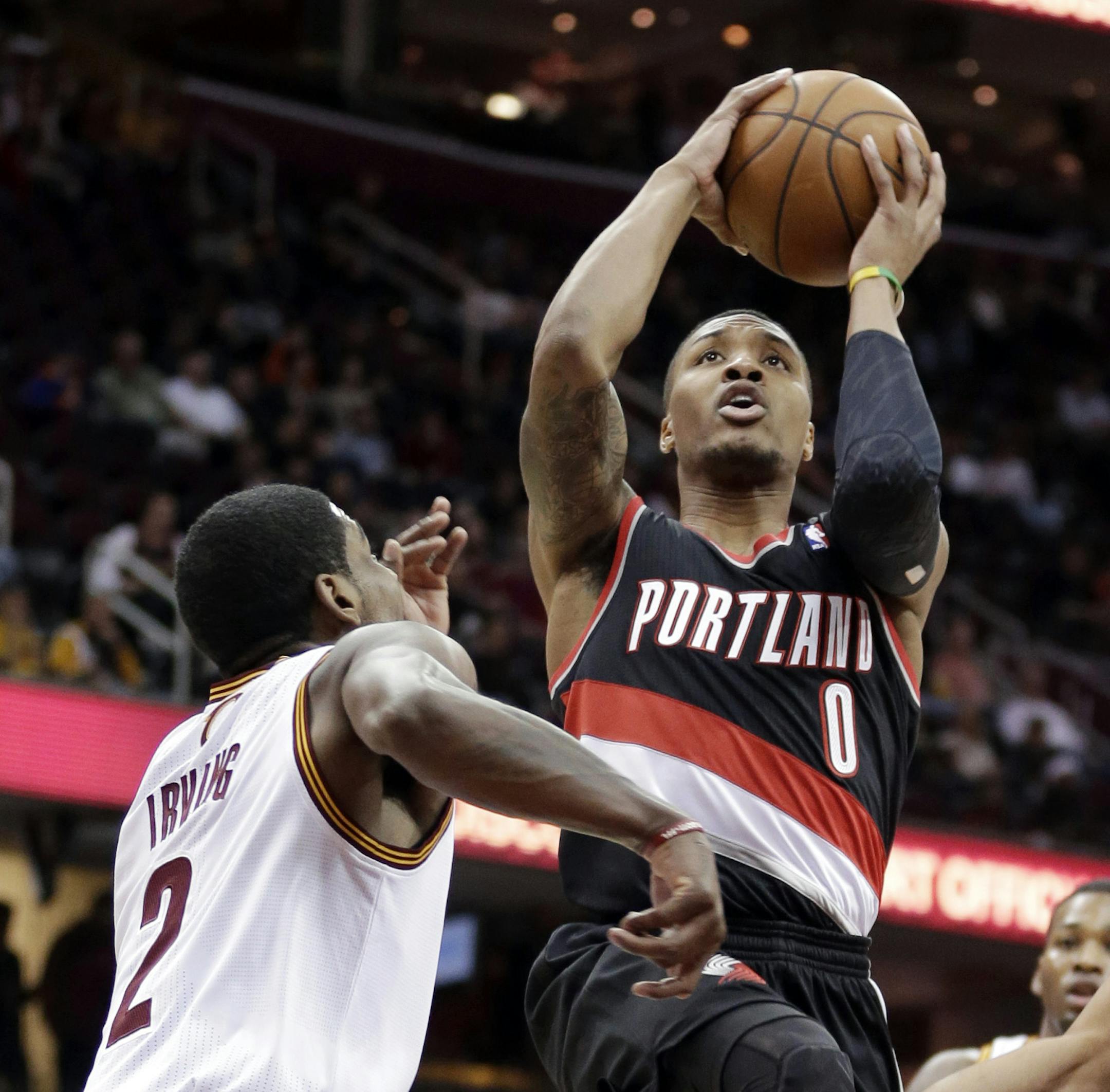 Portland Trail Blazers' Damian Lillard (0) jumps to the basket against Cleveland Cavaliers' Kyrie Irving (2) during the first quarter of an NBA basketball game Tuesday, Dec. 17, 2013, in Cleveland. (AP Photo/Tony Dejak)