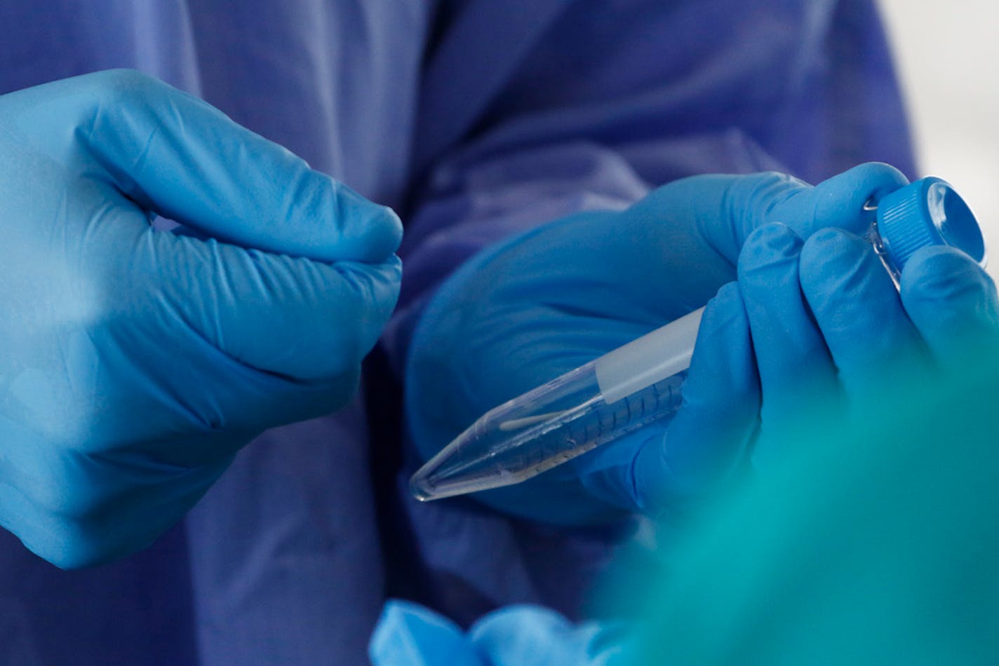 In this file photo, a medical student practices collecting a specimen for coronavirus testing,.