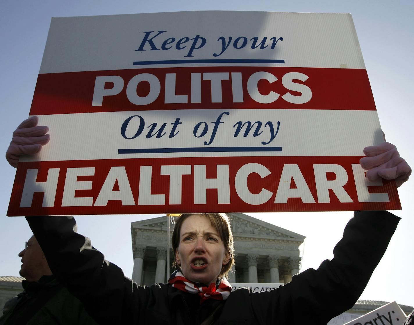 FILE - In this Tuesday, March 27, 2012 file photo, Amy Brighton from Medina, Ohio, who opposes health care reform, holds a sign in front of the Supreme Court in Washington during a rally as the court continues arguments on the health care law signed by President Barack Obama. Entrenched political divisions over "Obamacare" have driven most Republican-led states to turn their backs on the biggest expansion of the social safety net in a half century. (AP Photo/Charles Dharapak)