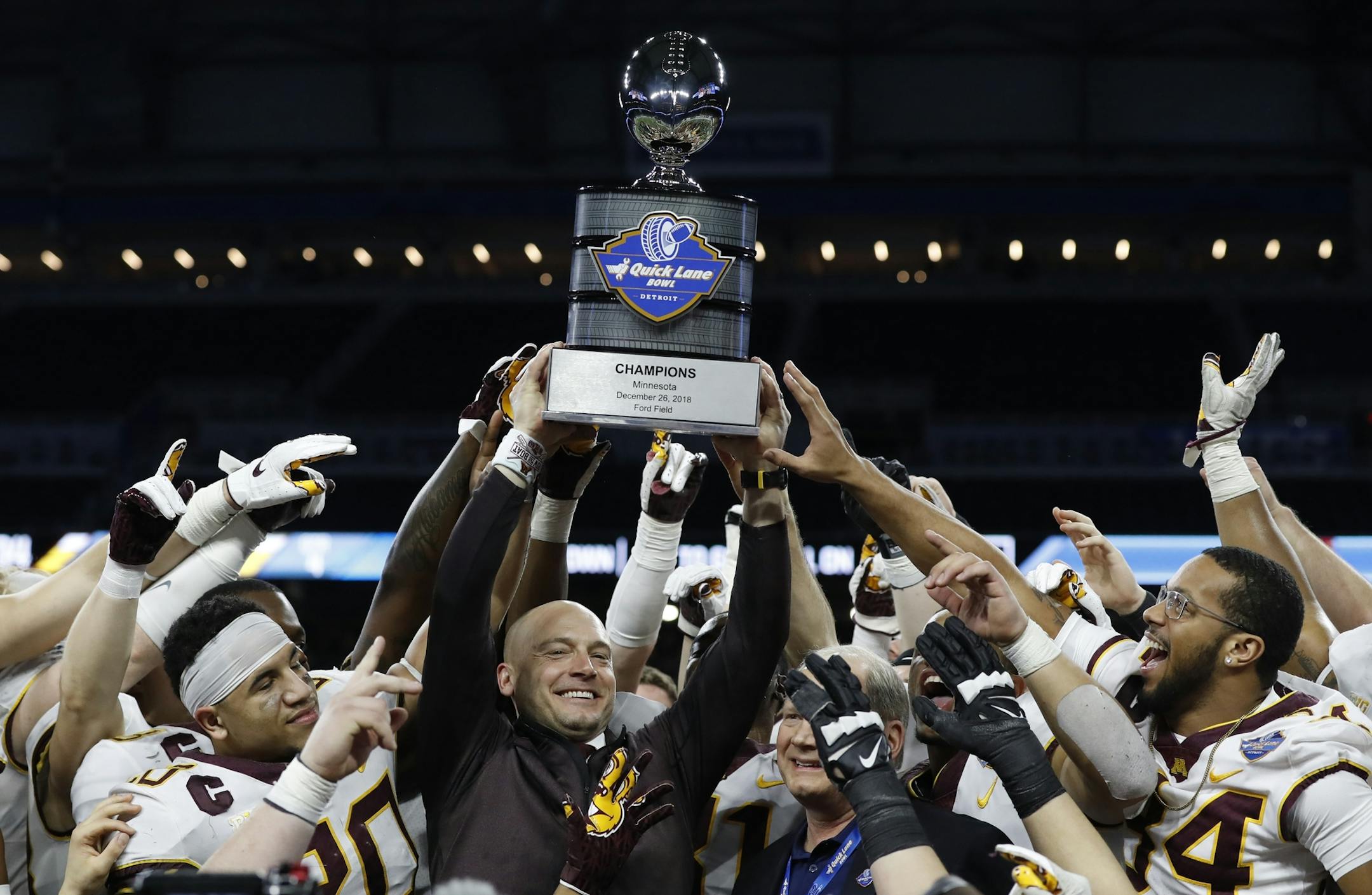 Minnesota head coach P.J. Fleck holds the champions trophy after the Quick Lane Bowl NCAA college football game against Georgia Tech, Wednesday, Dec. 26, 2018, in Detroit. Minnesota won 34-10. (AP Photo/Carlos Osorio)