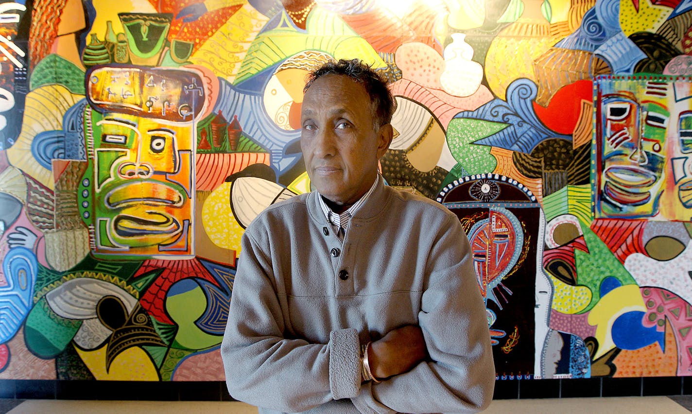 Abdulasis &#x201c;Aziz&#x201d; Osman stood in front of the mural he helped create at the Midtown Global Market in Minneapolis. His paintings &#x2014; signed &#x201c;Aziz&#x201d; &#x2014; adorn community spaces across the city.