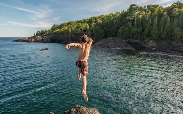 Summer activity at the Black Rocks of Presque Isle Park in Marquette, Michigan. The dark geological feature is a popular place for jumping into Lake S