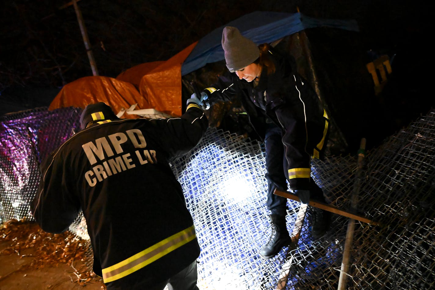 Minneapolis Crime Lab investigators climb over a downed fence while investigating a homicide Tuesday, Dec. 12, 2023 in the Nenookaasi encampment at East 23rd St and 13th Ave South in Minneapolis, Minn.. ] AARON LAVINSKY • aaron.lavinsky@startribune.com