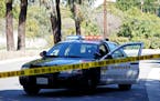 FILE - In this Feb. 23, 2021, file photo, a police car blocks a road in a suburb of Los Angeles. The Associated Press says it will no longer publish t