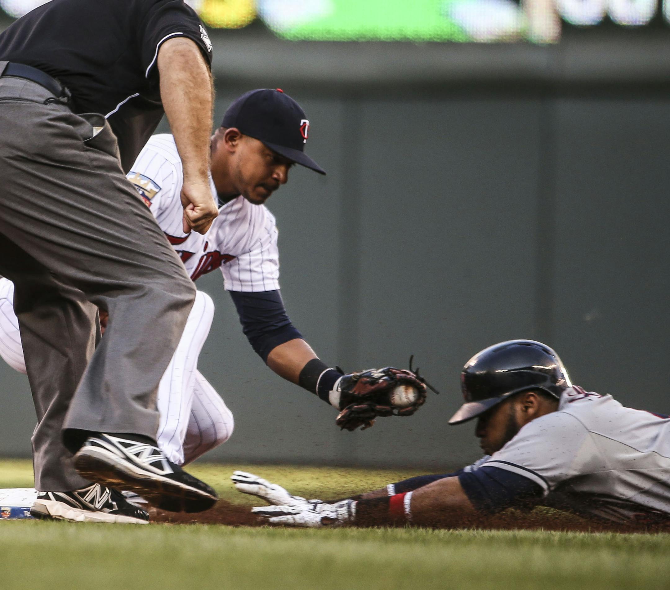 Cleveland’s Carlos Santana narrowly beat the tag of Twins shortstop Eduardo Escobar for a double in the second inning.
