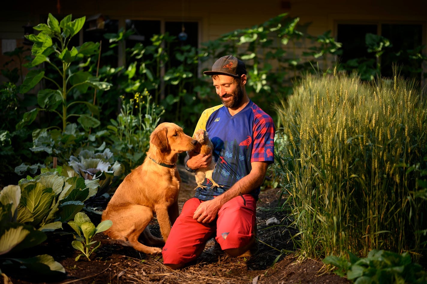 It's the country life for Derrick Justin, shown at his home with his golden retriever, Aura, and Darla, one of his two dozen chickens.