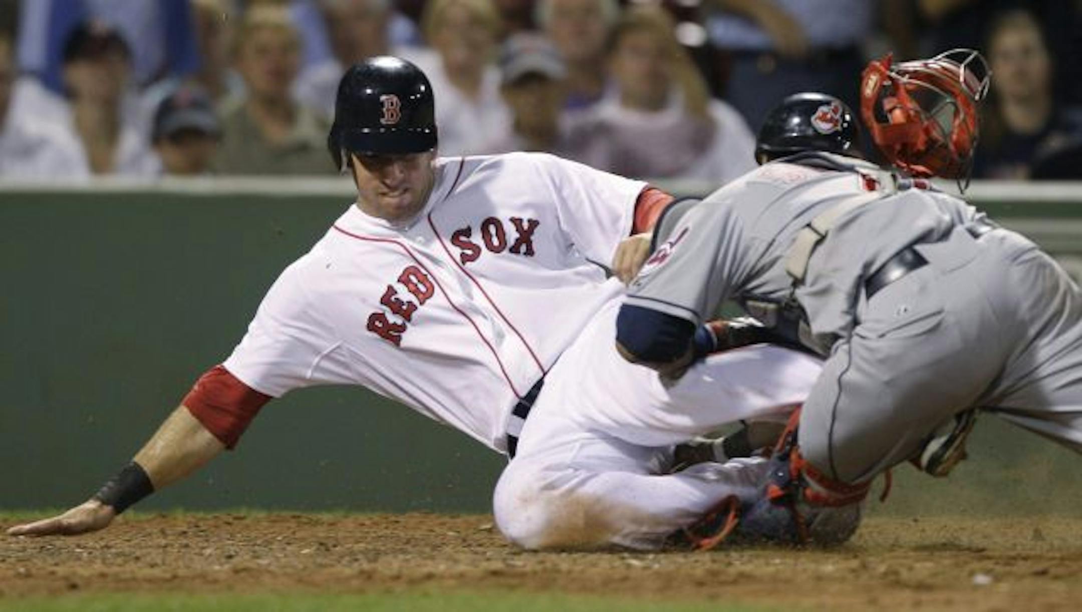 Boston Red Sox's Ryan Kalish collides with Cleveland Indians catcher Carlos Santana, who blocked the plate and tagged out Kalish who was trying to score on a single by Daniel Nava in the seventh inning of a baseball game in Boston, Monday, Aug. 2, 2010. Santana was carted off the field with his left leg in an air cast.
