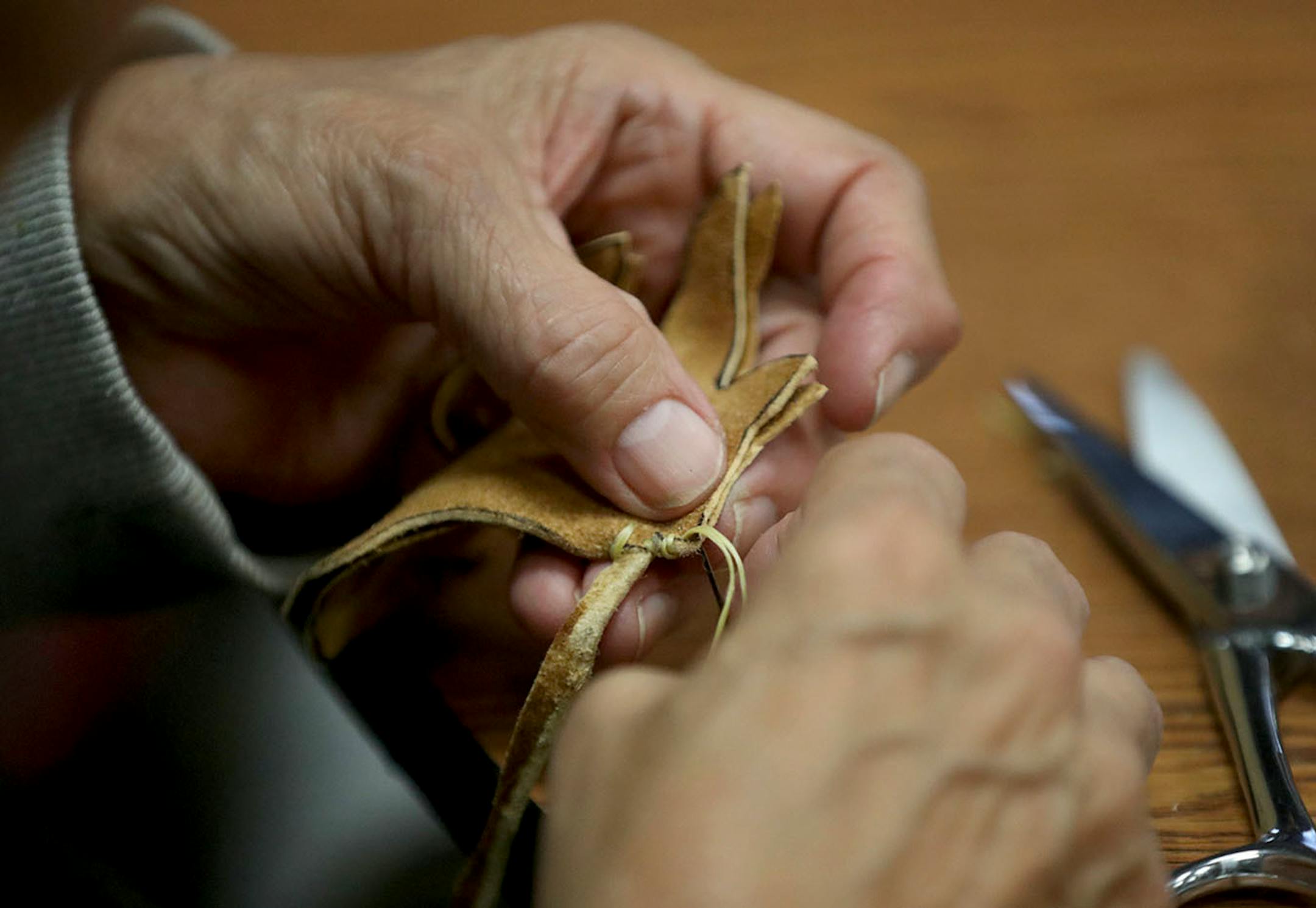 A Lower Sioux Community member sews a traditional tobacco pouch from deer hide at the community center.