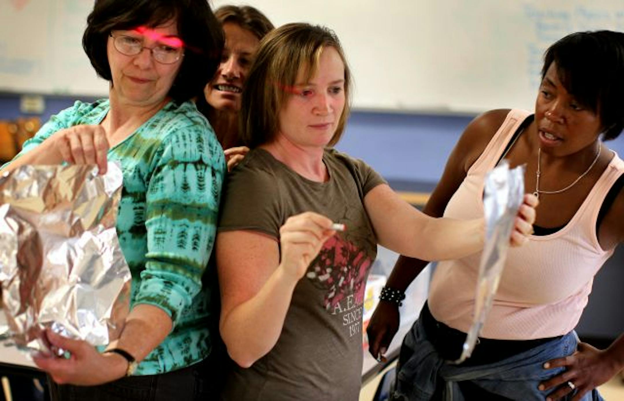 From left, Richfield teachers Sue Peploe, Bobbie Nelson, Carrie Allen and Melanie Lawrence-Smith conduct a science experiment involving a red light and foil during a training session led by St. Catherine University faculty. They're preparing for the opening of Richfield's new STEM school.