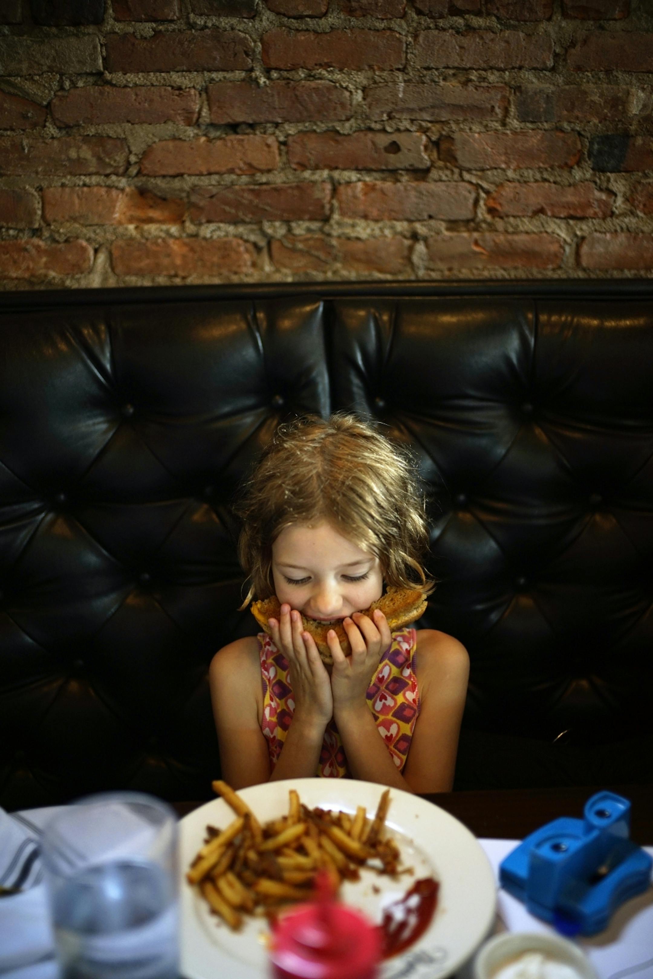 Camera Powell, 6, enjoys a grilled cheese sandwich at Landon Schoenfeld's new restaurant, Nighthawks which has been open for three months.