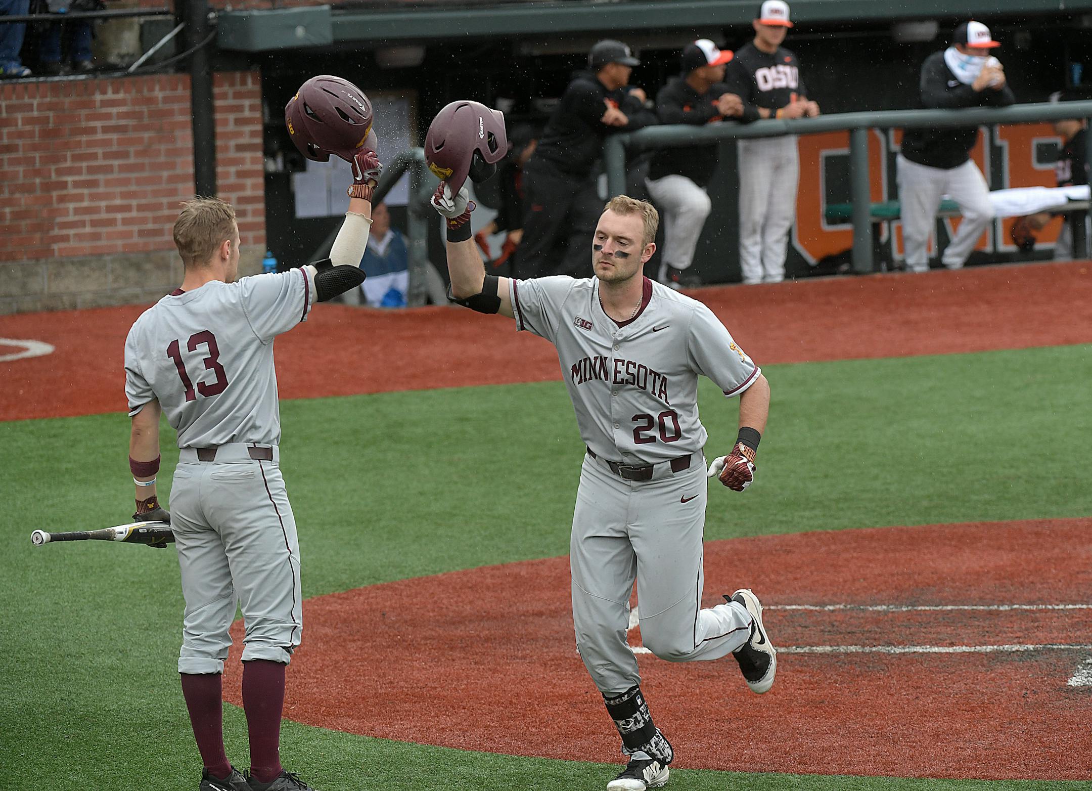 Minnesota's Toby Hanson (20) taps helmets with Luke Pettersen (13) after Hanson hit a solo home run off Oregon State's Luke Heimlich during the opening game of an NCAA college baseball tournament super regional in Corvallis, Ore., Friday, June 8, 2018. (Mark Ylen/Albany Democrat-Herald via AP)