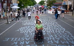 Innocynce Johnson roller skates while pushing her sister, HeavenRain Bible, at George Floyd Square.