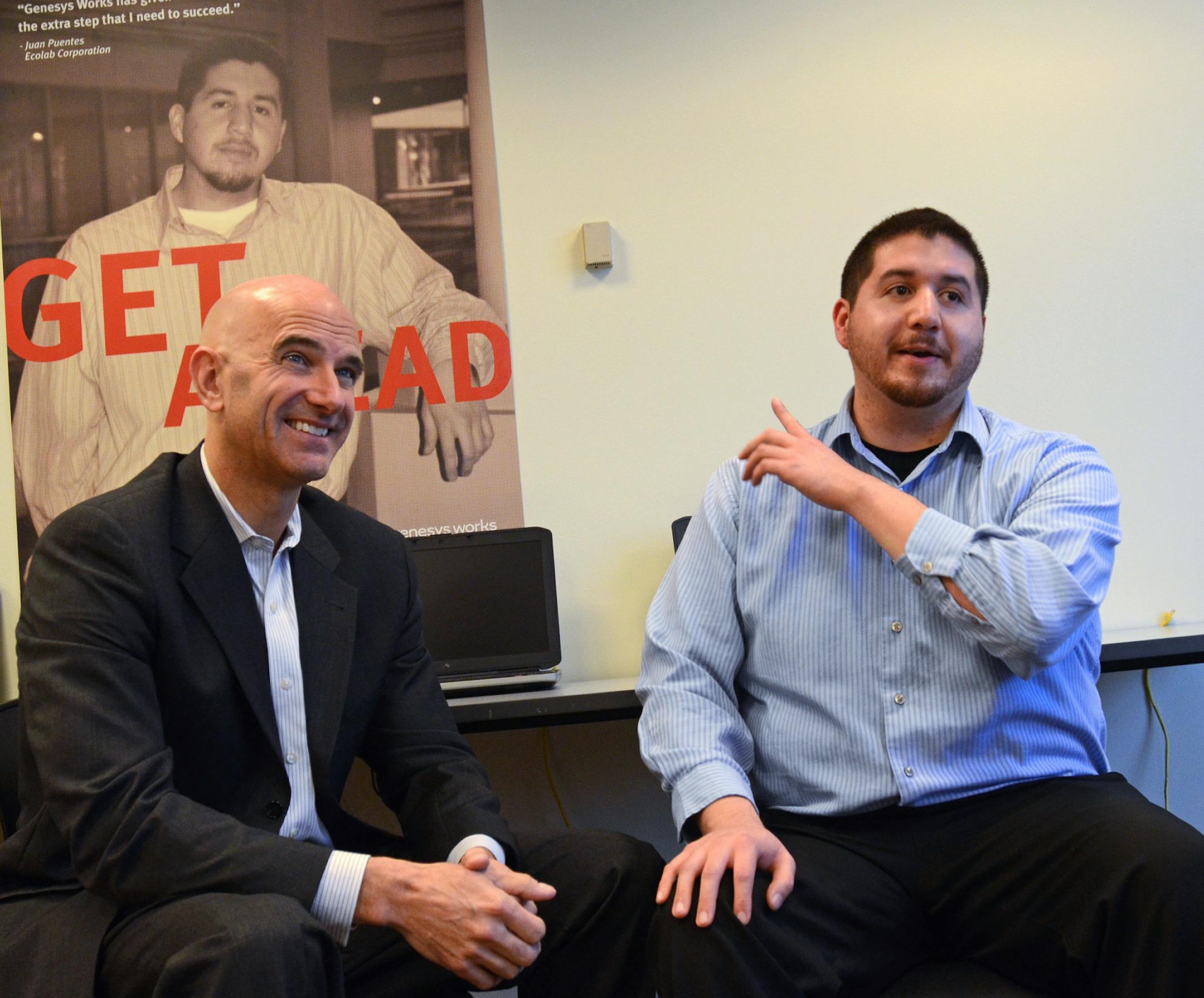 (Left to right)Jeff Tollefson, executive director of Genesys Works, talked with Juan Puentes, who now works at Ecolab. Puentes is a success story at Genesys Works, a company that bridges the gap between education and business.) In the background is a poster featuring Puentes when he was a student at Genesys Works. ] Joey McLeister,Special to the Star Tribune,St.Paul,MN October16,2013