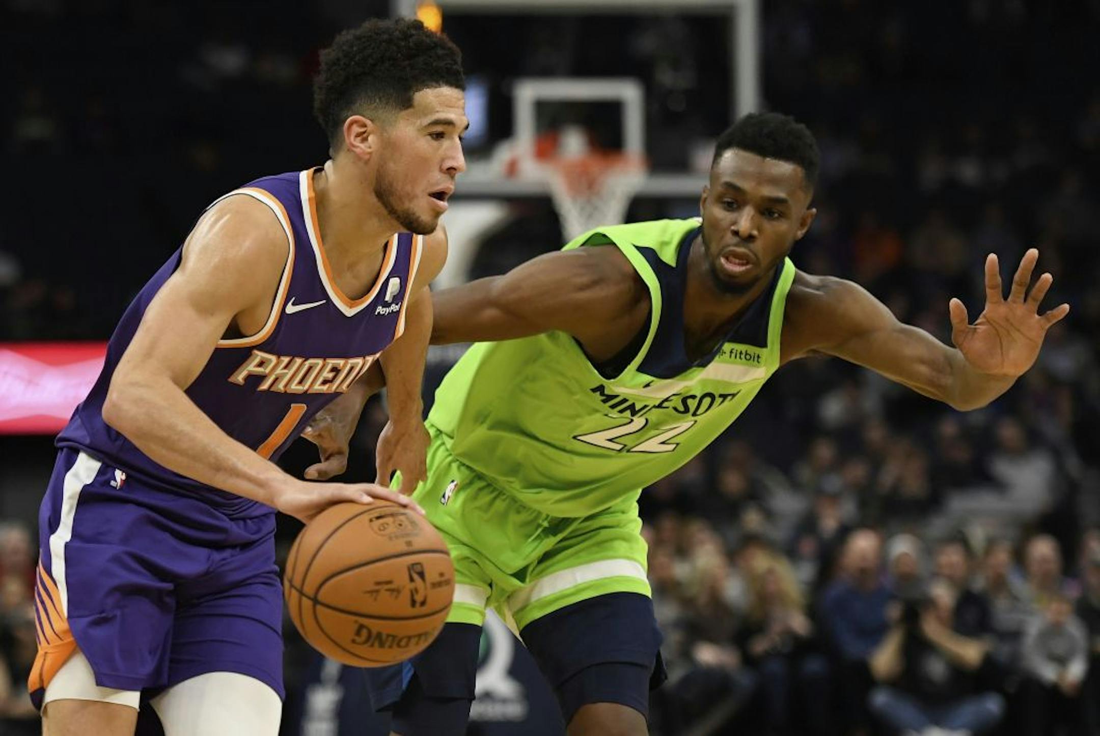 Minnesota Timberwolves' Andrew Wiggins (22) guards Phoenix Suns' Devin Booker (1) during the first quarter of an NBA basketball game Saturday, Nov. 23, 2019, in Minneapolis. The Suns won 100-98.