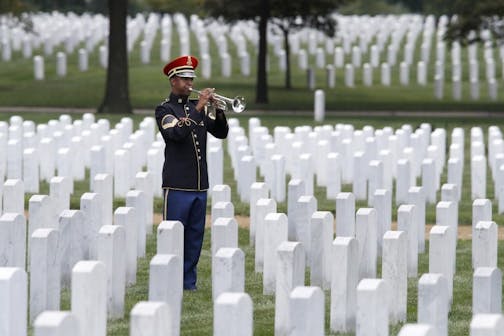 FILE -- A soldier with the 3rd Infantry Regiment, also known as the Old Guard, plays taps during the burial service of retired Army Col. Roger Brown, of Arlington, Va., at Arlington National Cemetery, in Arlington, Va., Monday, Aug. 6, 2018.