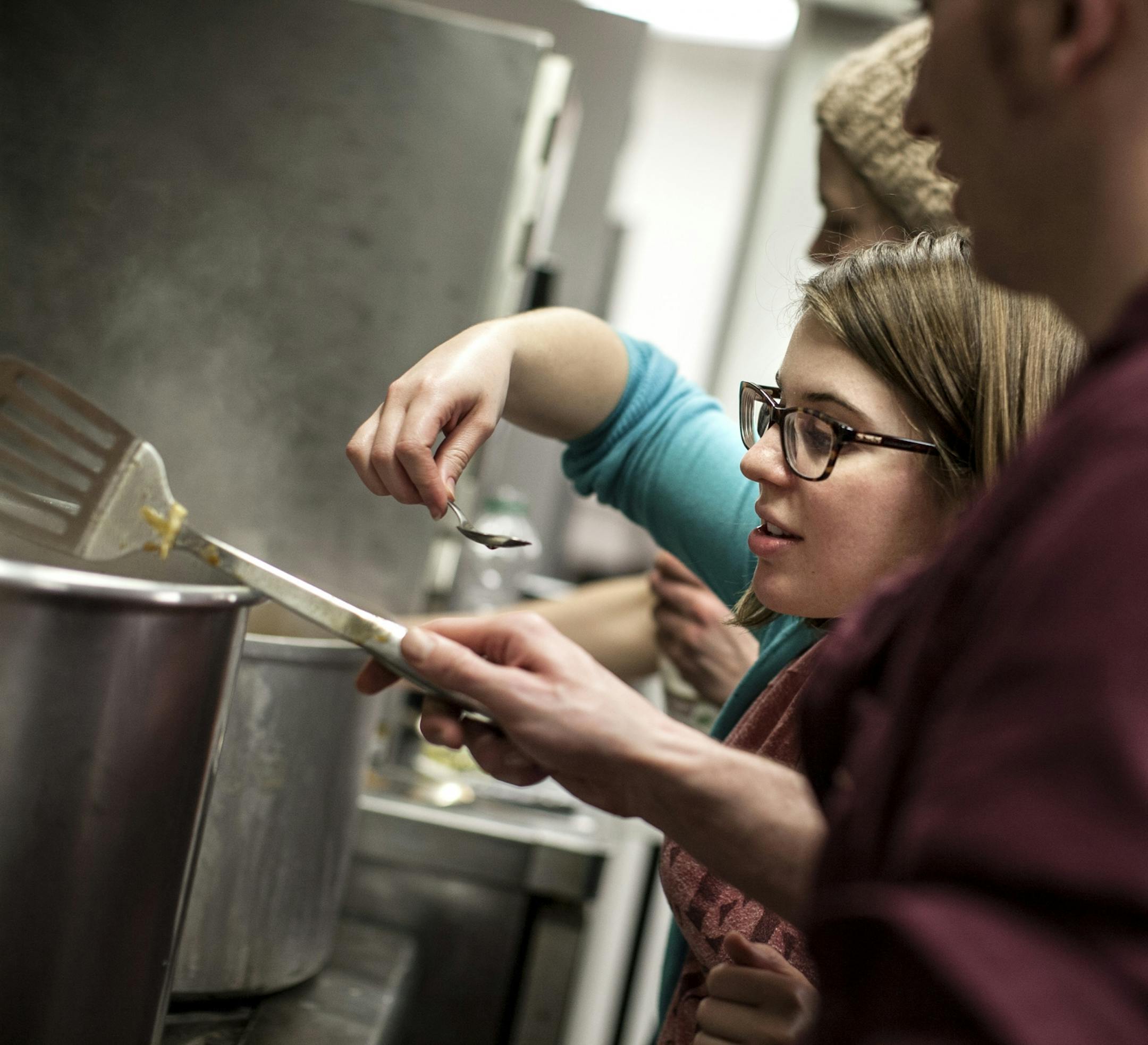 Volunteer Caitlin Duff taste-tests the posole at Eat for Equity's community feast benefitting Urban Ventures at the Urban Ventures headquarters in Minneapolis January 31, 2015.
