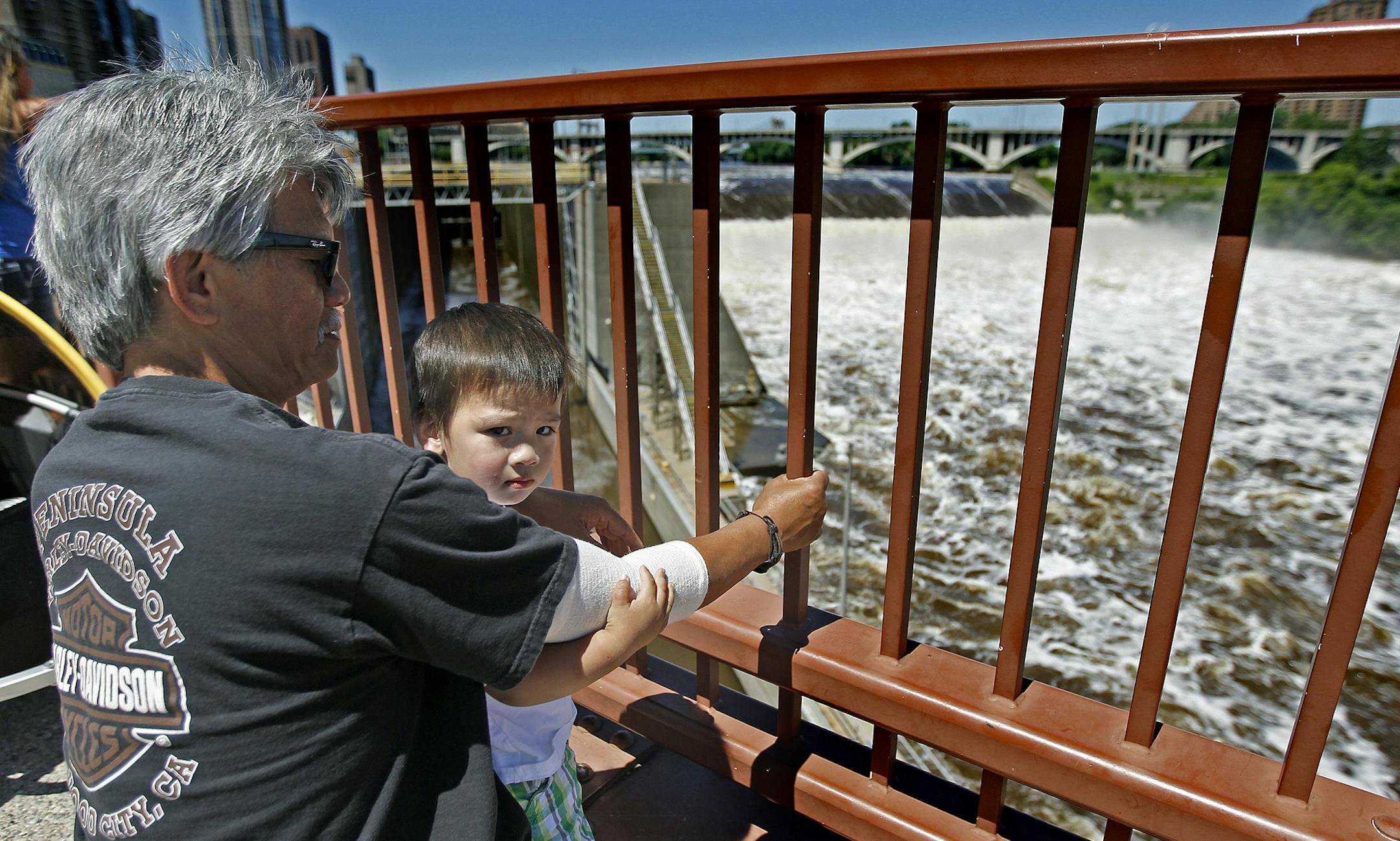 Larry Paguio and his grandson Alex Paguio, 2, of Brooklyn Center, watched the raging waters from the Stone Arch Bridge, Thursday, June 27, 2013. Three locks on the Mississippi River in the Twin Cities closed to all boat traffic due to high water. (ELIZABETH FLORES/STAR TRIBUNE) ELIZABETH FLORES • eflores@startribune.com