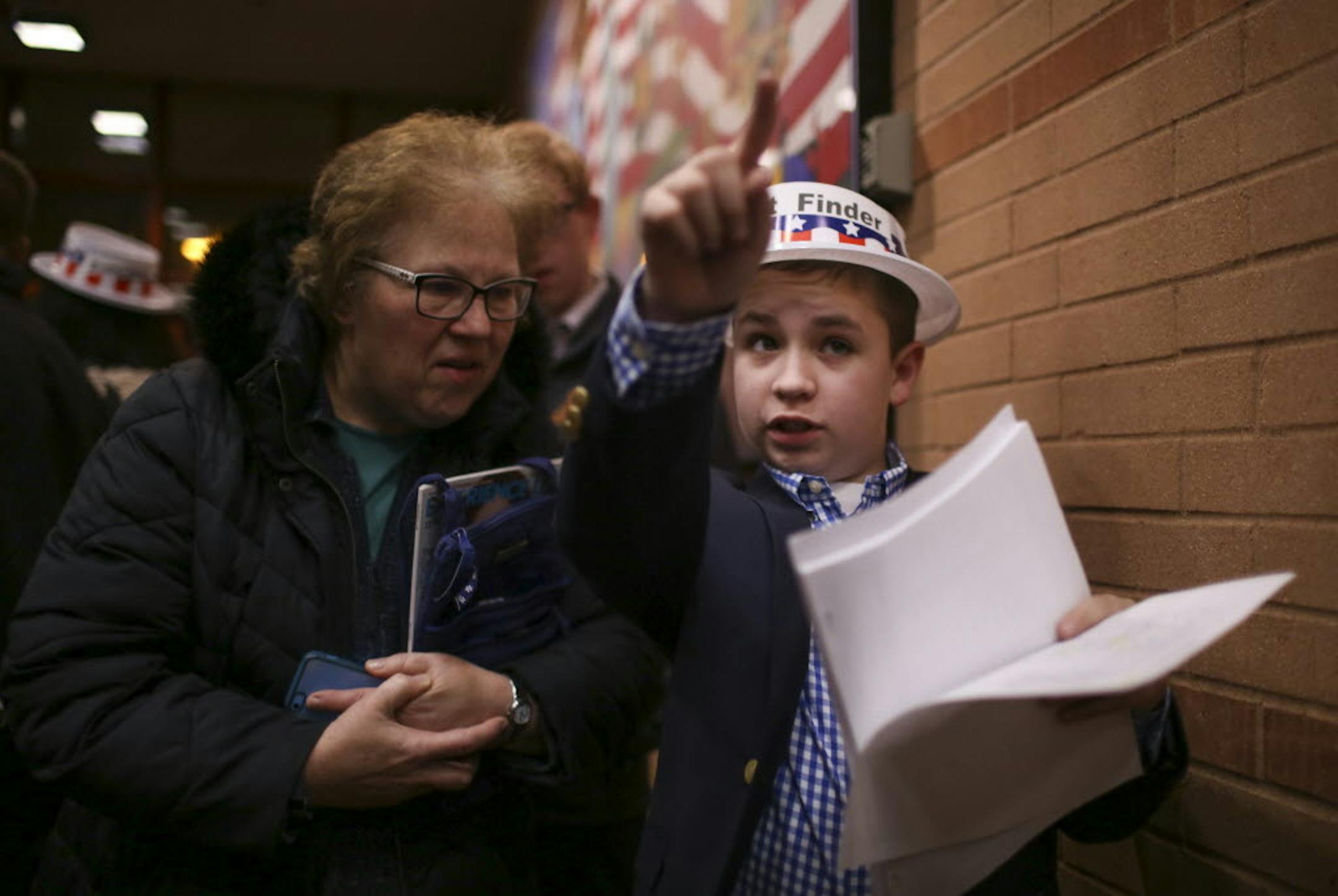 Volunteer precinct finder Keaton Leithead, 13, directed Nancy Schaffert of Eagan to her caucus Tuesday night at Black Hawk Middle School.